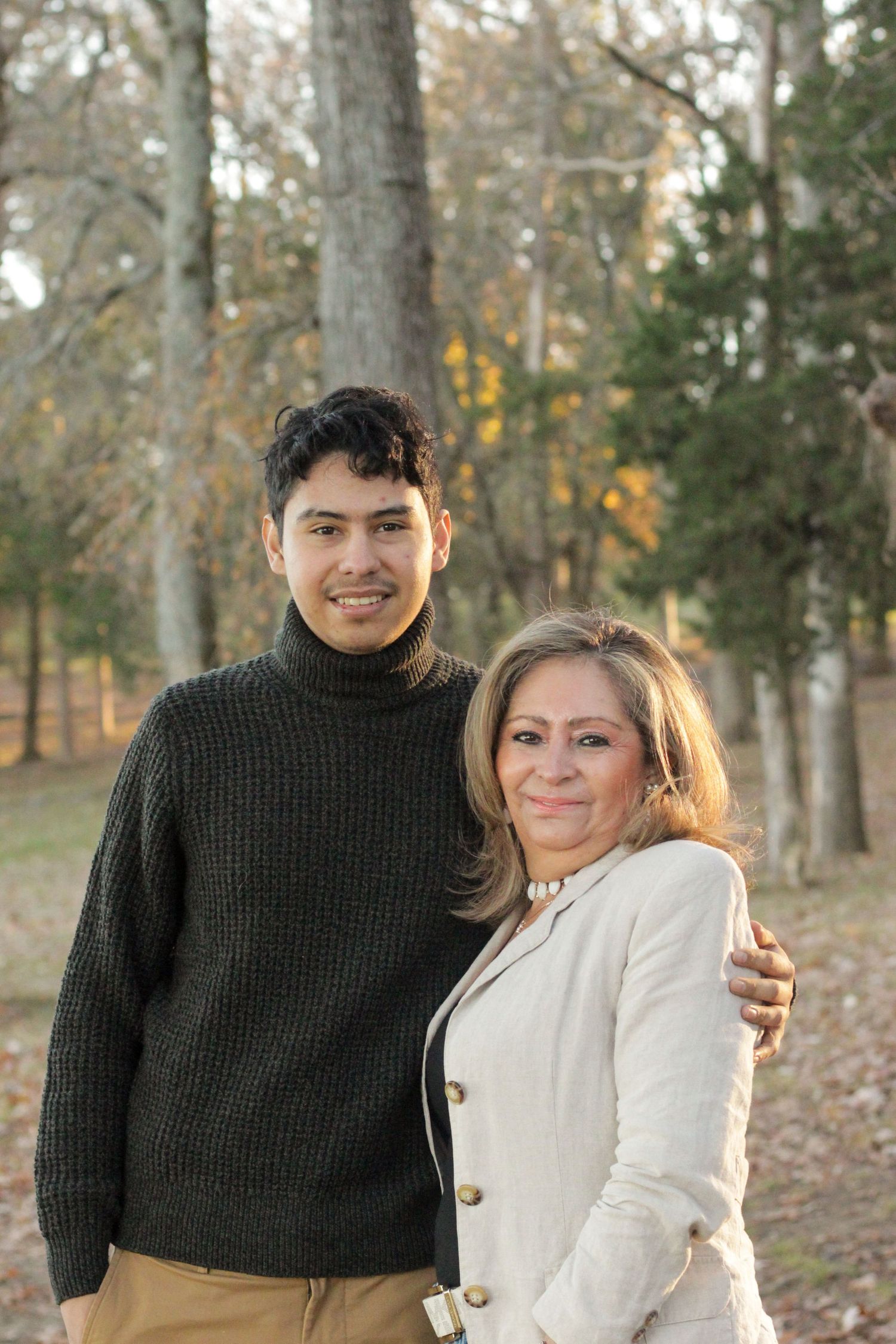 A warm autumn portrait of two people in black and cream sweaters smiling outdoors.