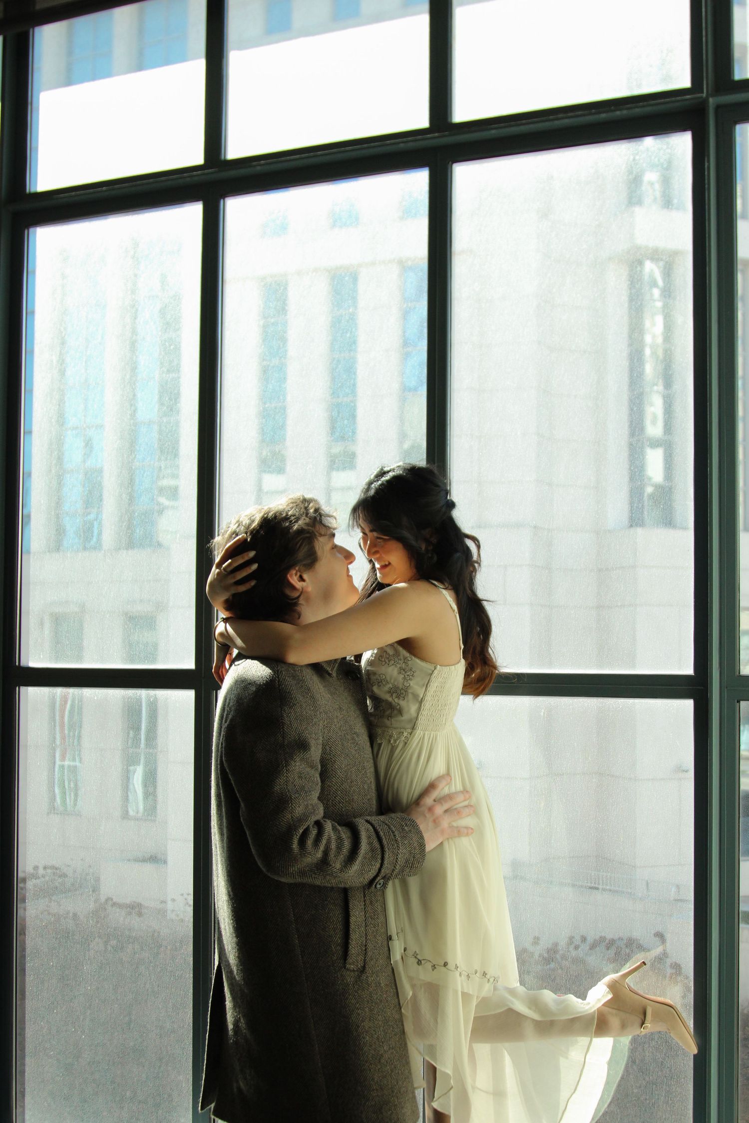 A romantic embrace by a window with bright natural backlighting.