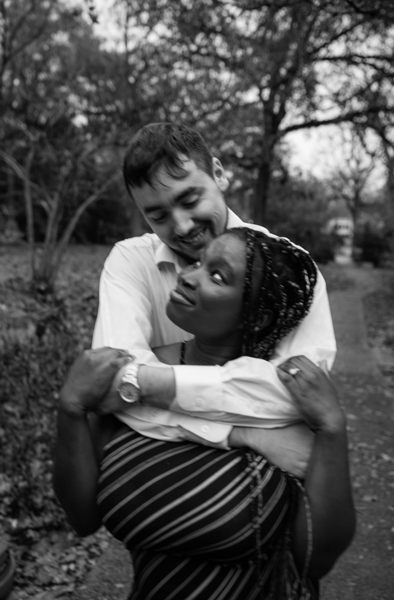 Black and white romantic photo sequence showing a couple embracing and sharing tender moments in a park setting.