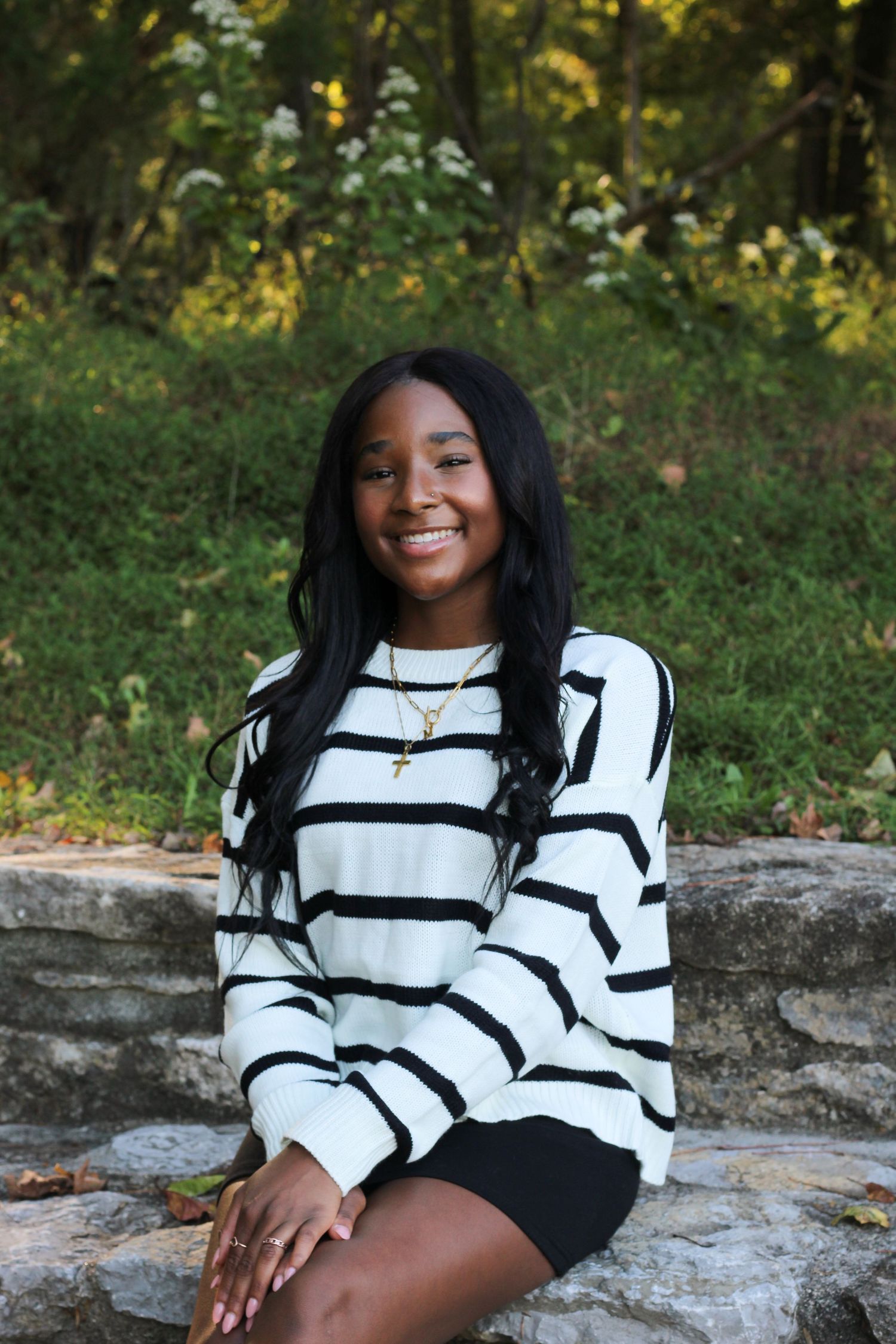 Outdoor portrait series featuring person in striped sweater sitting on natural stone formation.