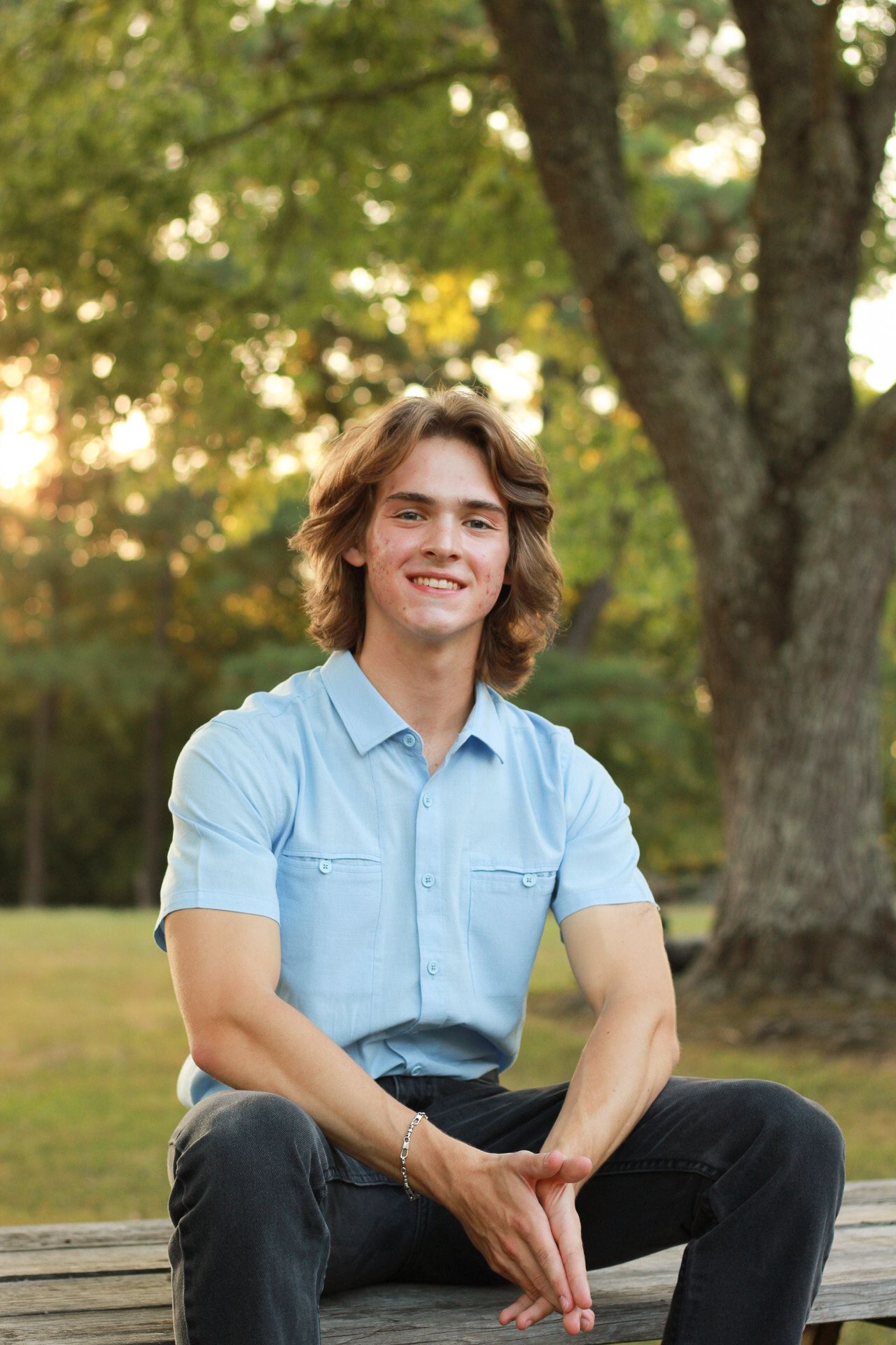 Casual outdoor portrait series showing someone in a light blue shirt sitting on a wooden bench.