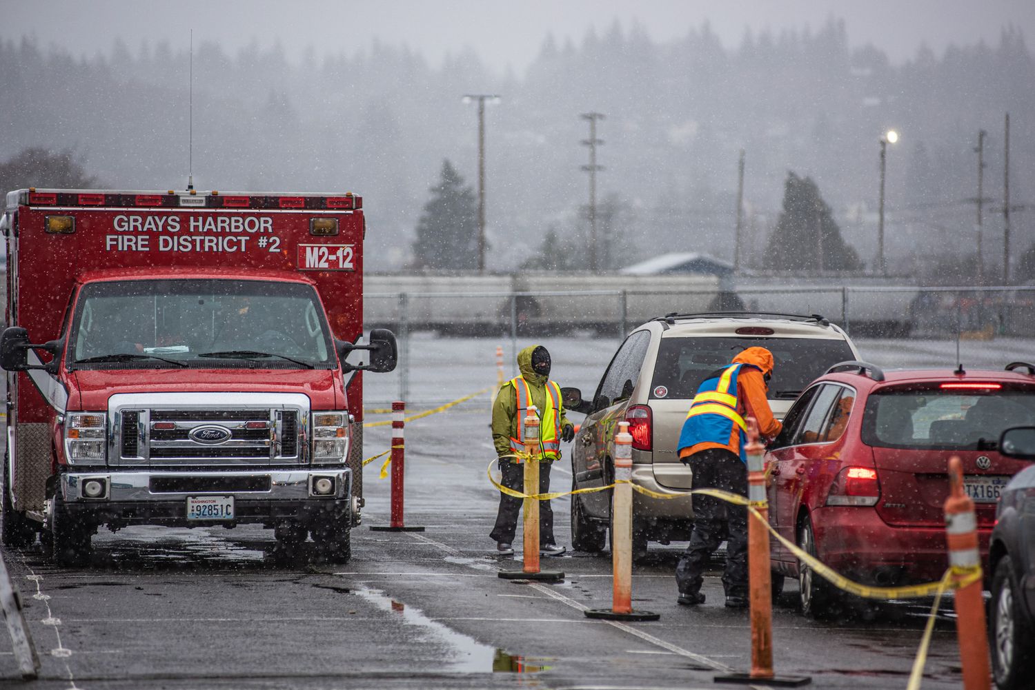 Grays Harbor Fire District 2 emergency truck parked beside two firefighters in safety gear near cars and traffic cones on a wet, foggy road.
