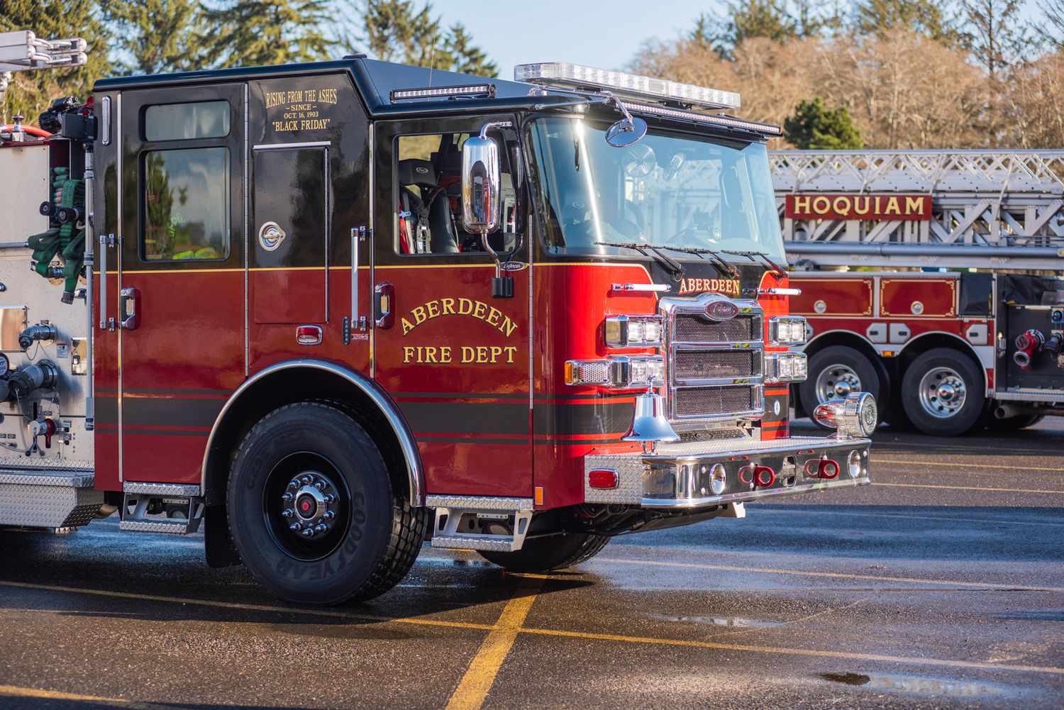 Red Aberdeen Fire Department fire engine parked on wet pavement beside a ladder truck on a clear day.