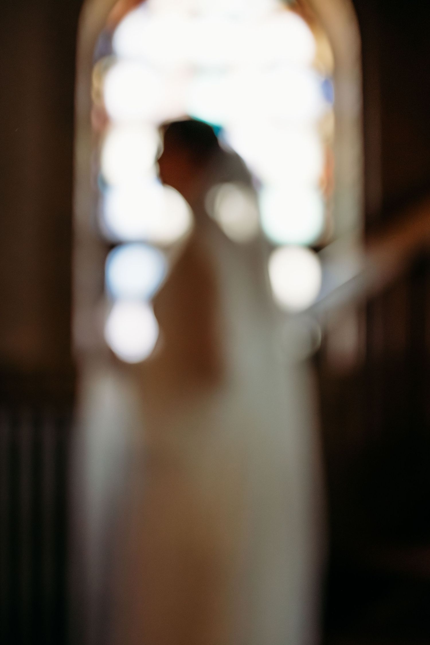 A sequence shows the silhouette of a Catholic bride in wedding attire moving through a sunlit doorway with soft bokeh lighting.