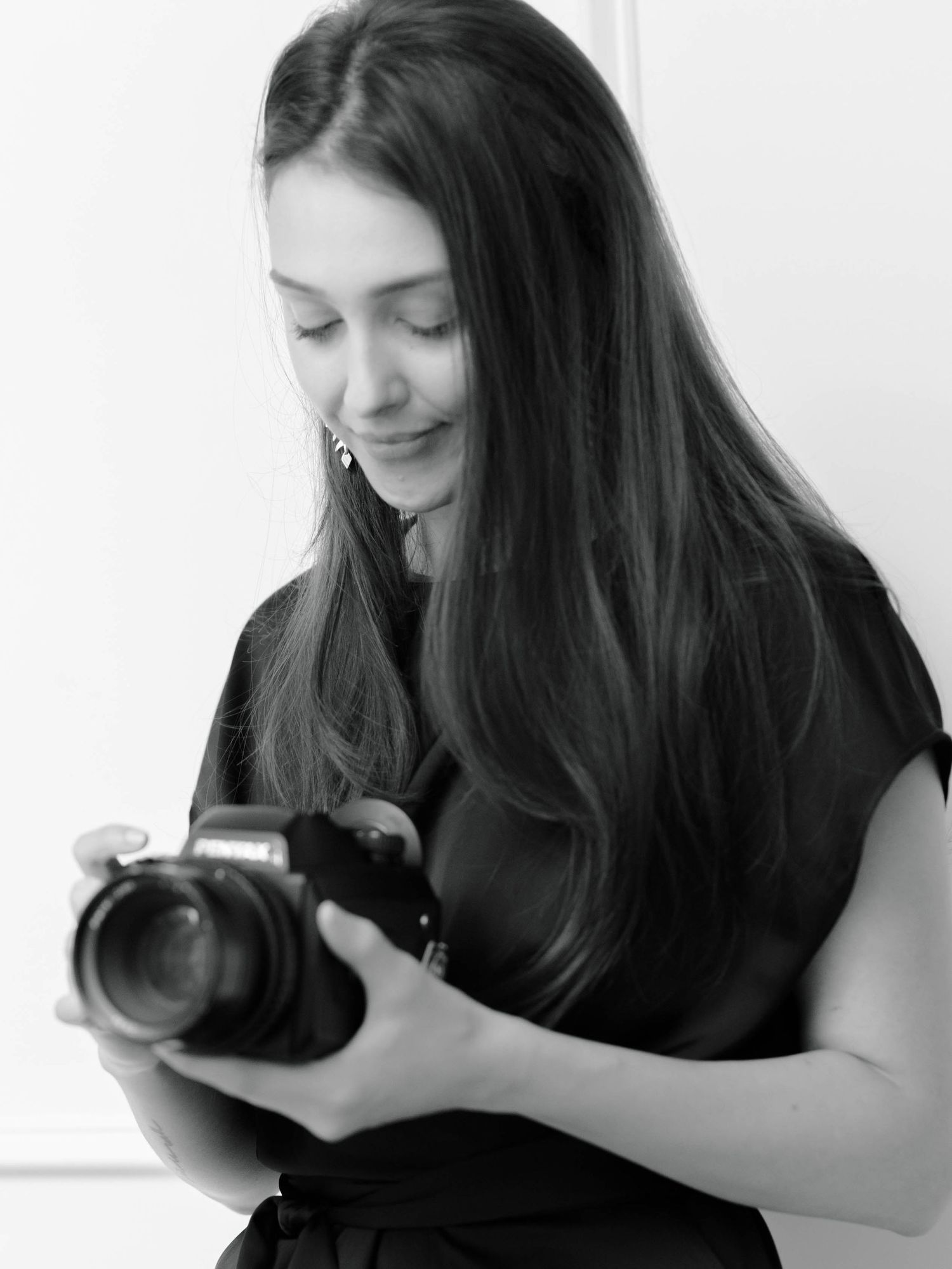 Black and white close-up of female photographer looking down at her professional camera.