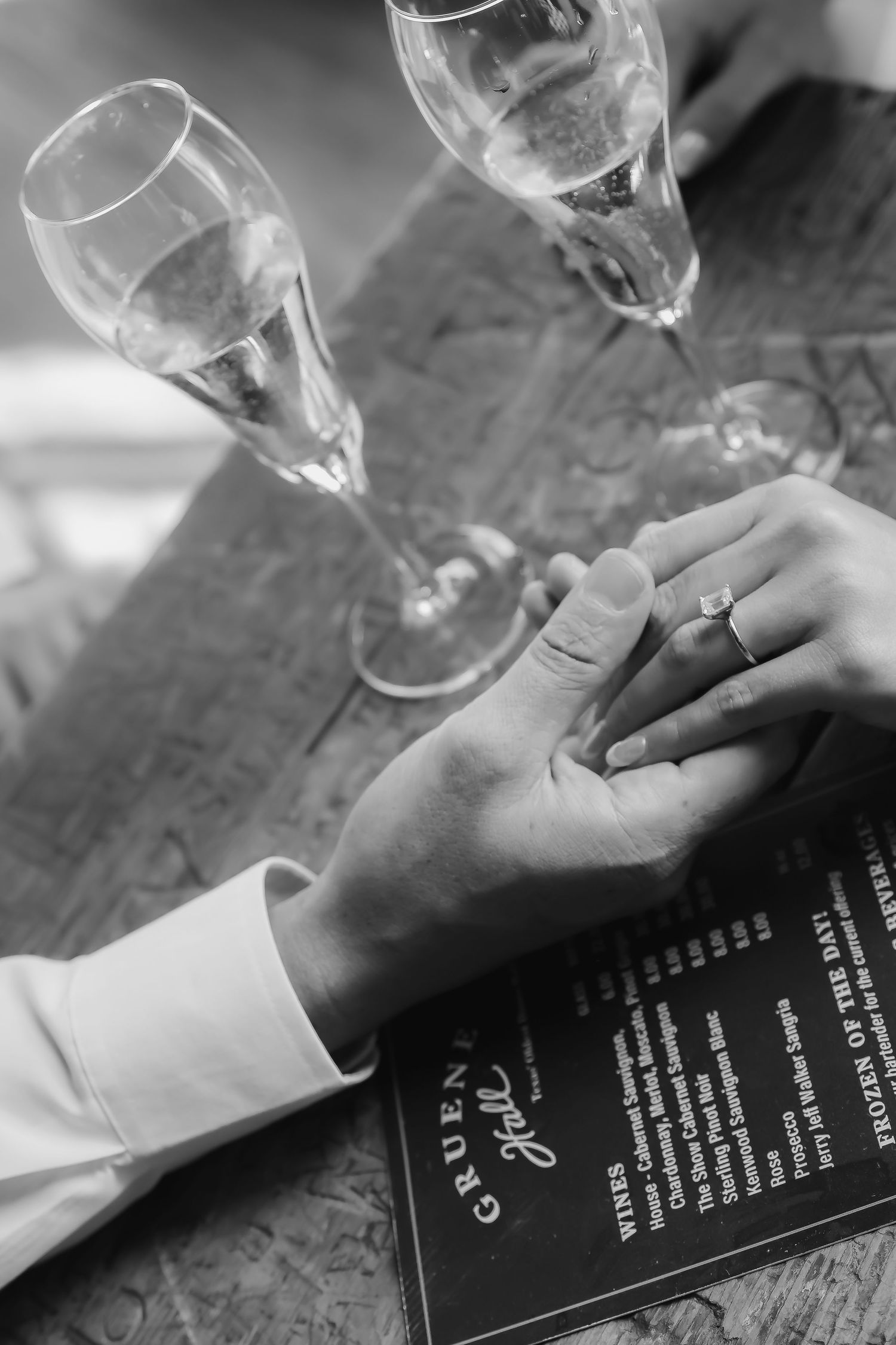 Black and white photo of champagne glasses and wedding rings on menu card.