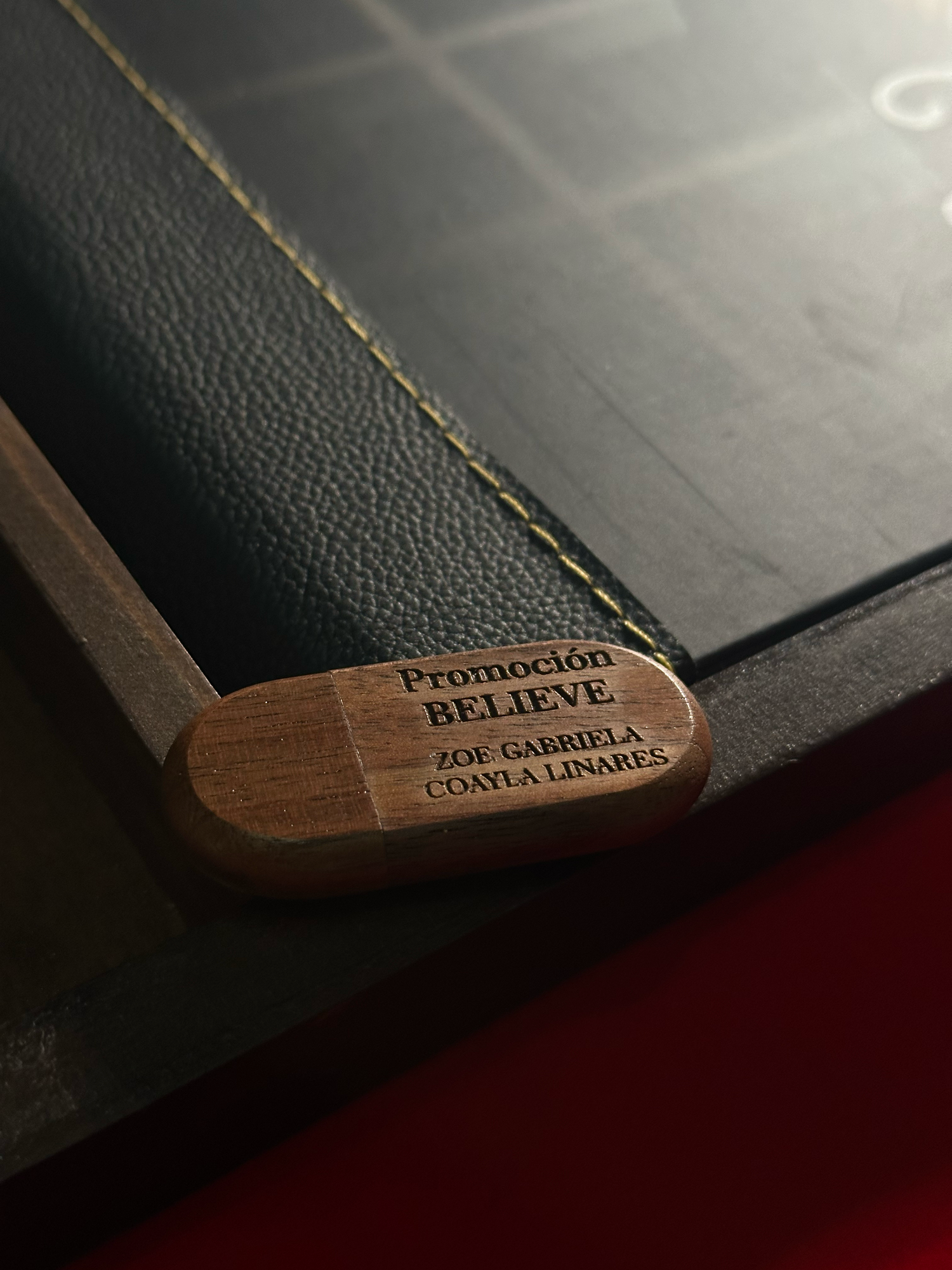 Close-up sequence showing text being revealed on a wooden bookmark with dark leather background.