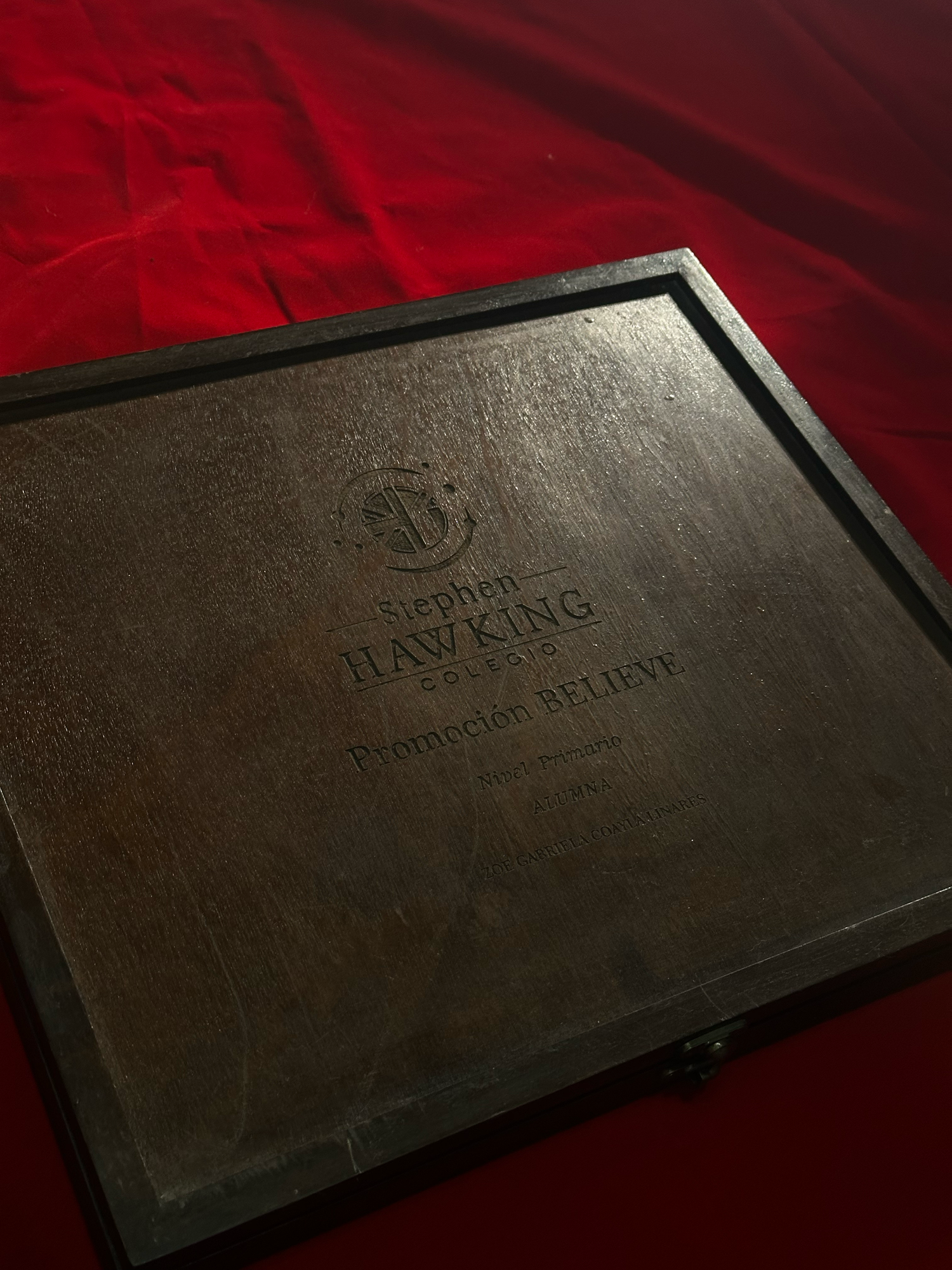 Leather-bound book or portfolio shown at different angles on a deep red velvet background.