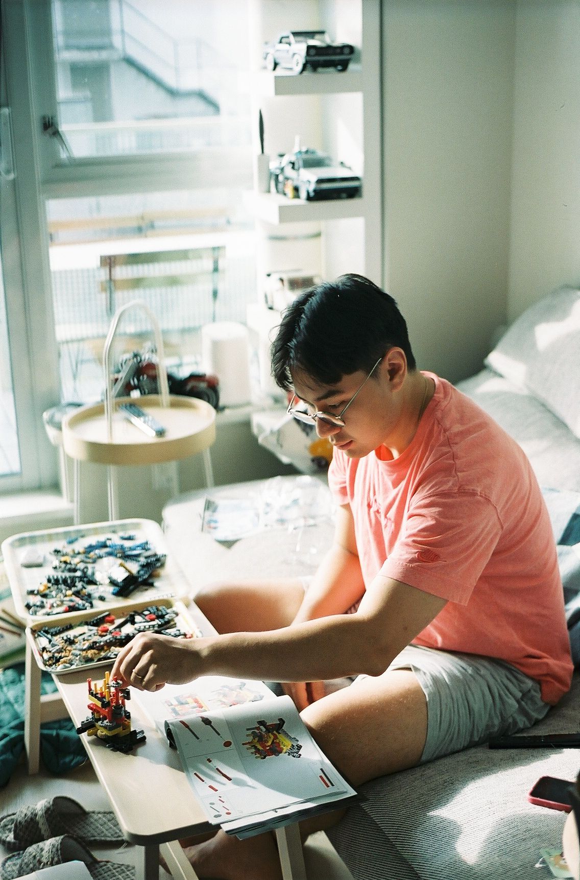 Person working on creative project with art supplies in sunlit room.