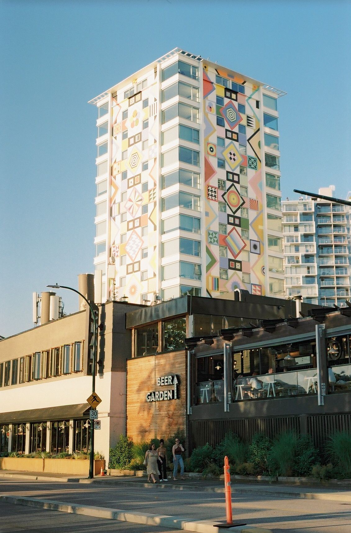 Modern apartment building with geometric art patterns decorating its facade next to a commercial building in the city.