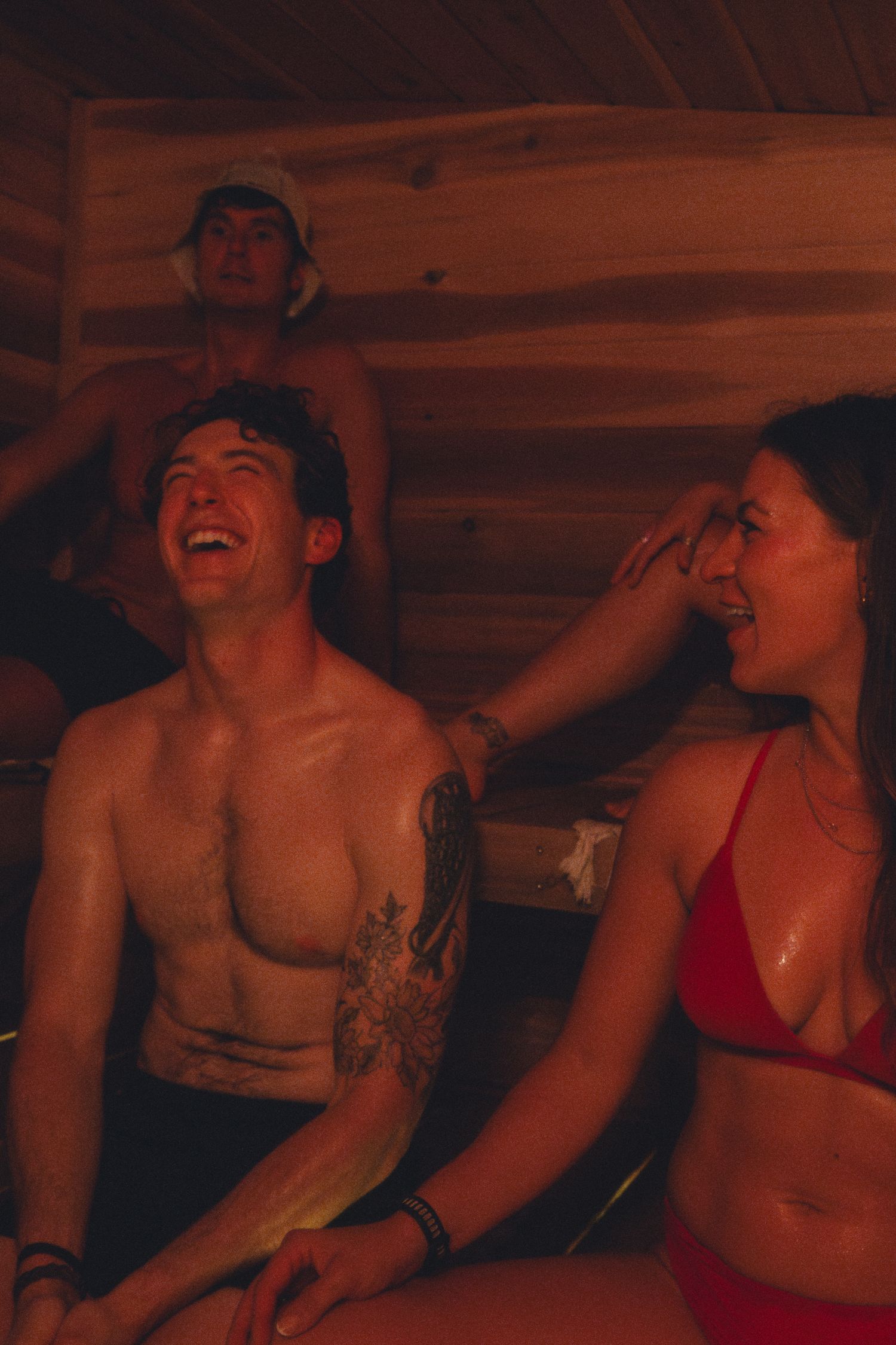 Friends laughing together in warm-lit wooden interior.