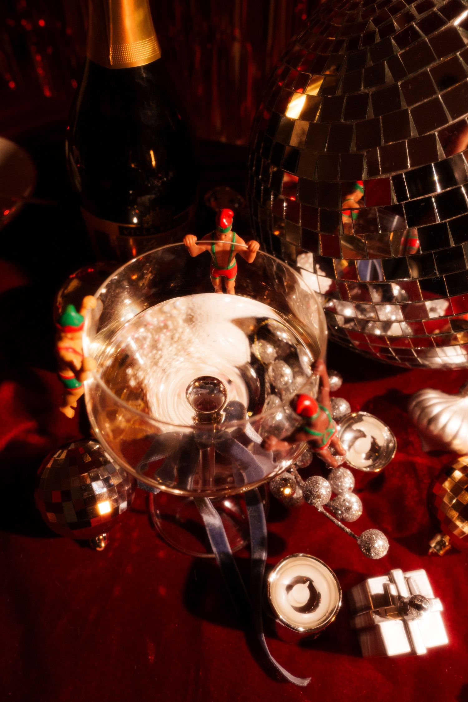 Overhead view of champagne glass with holiday decorations and disco ball reflections.