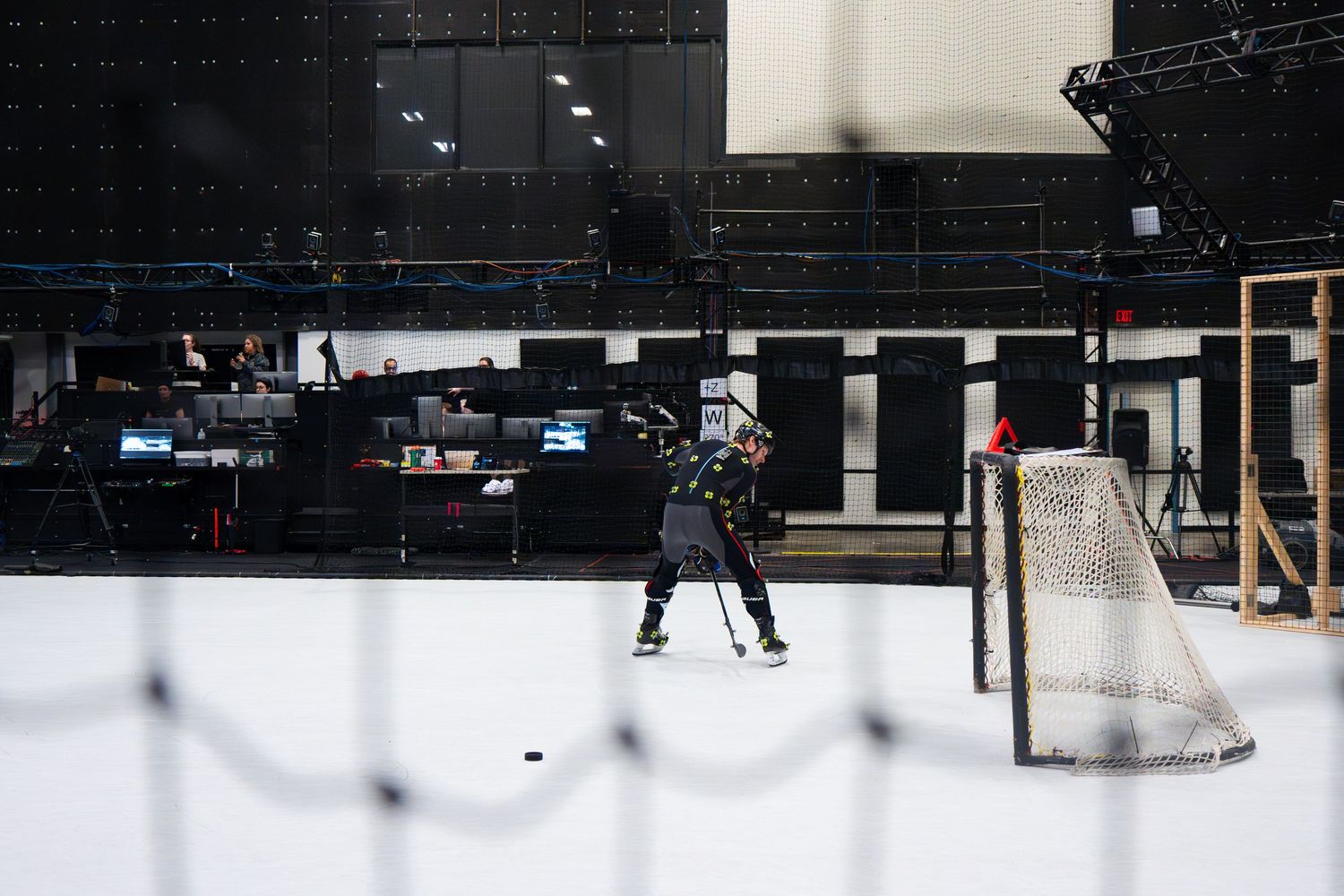 Wide shot of hockey goal setup in dark studio with motion capture equipment visible.