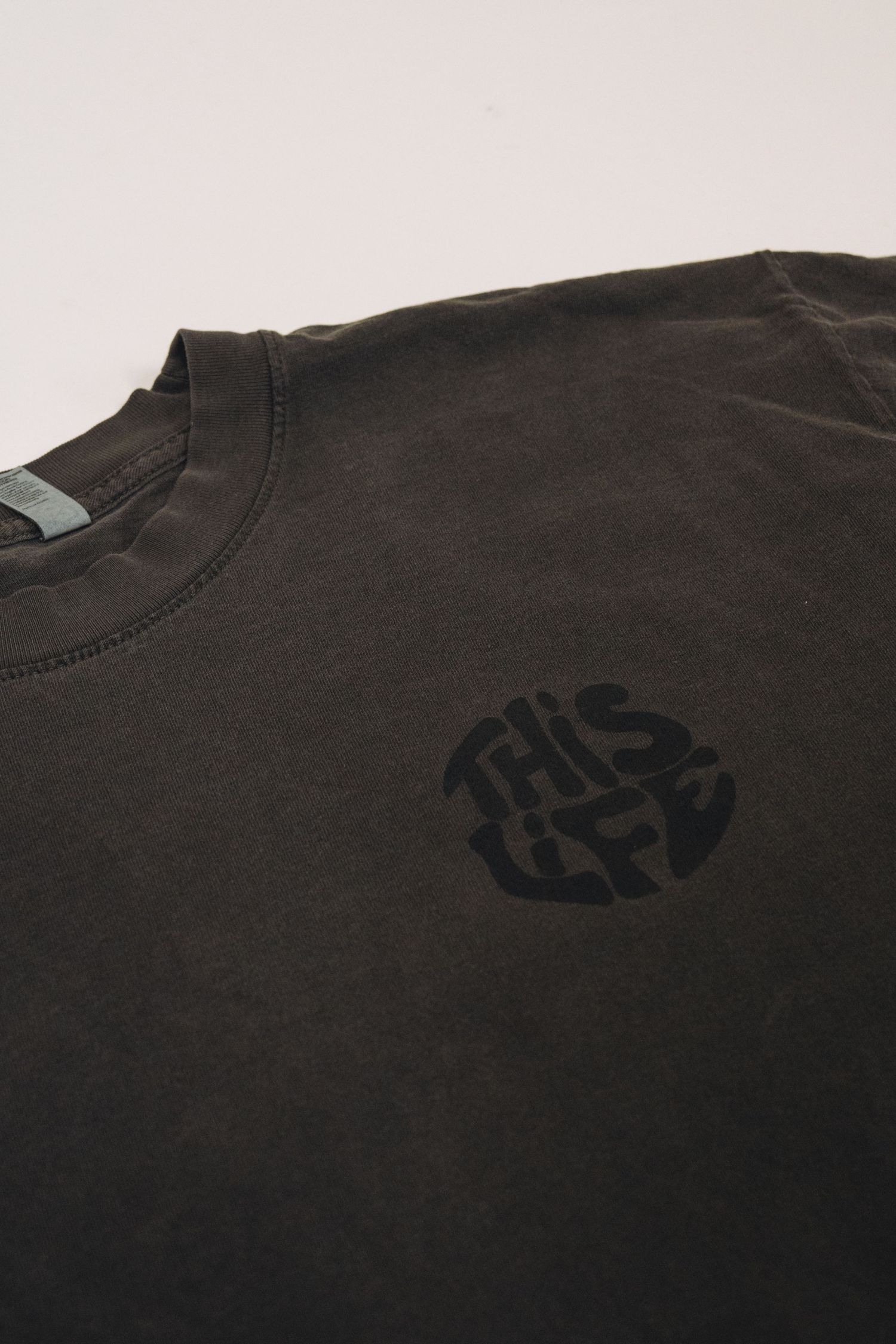 Black t-shirt with small dark logo printed on chest area.