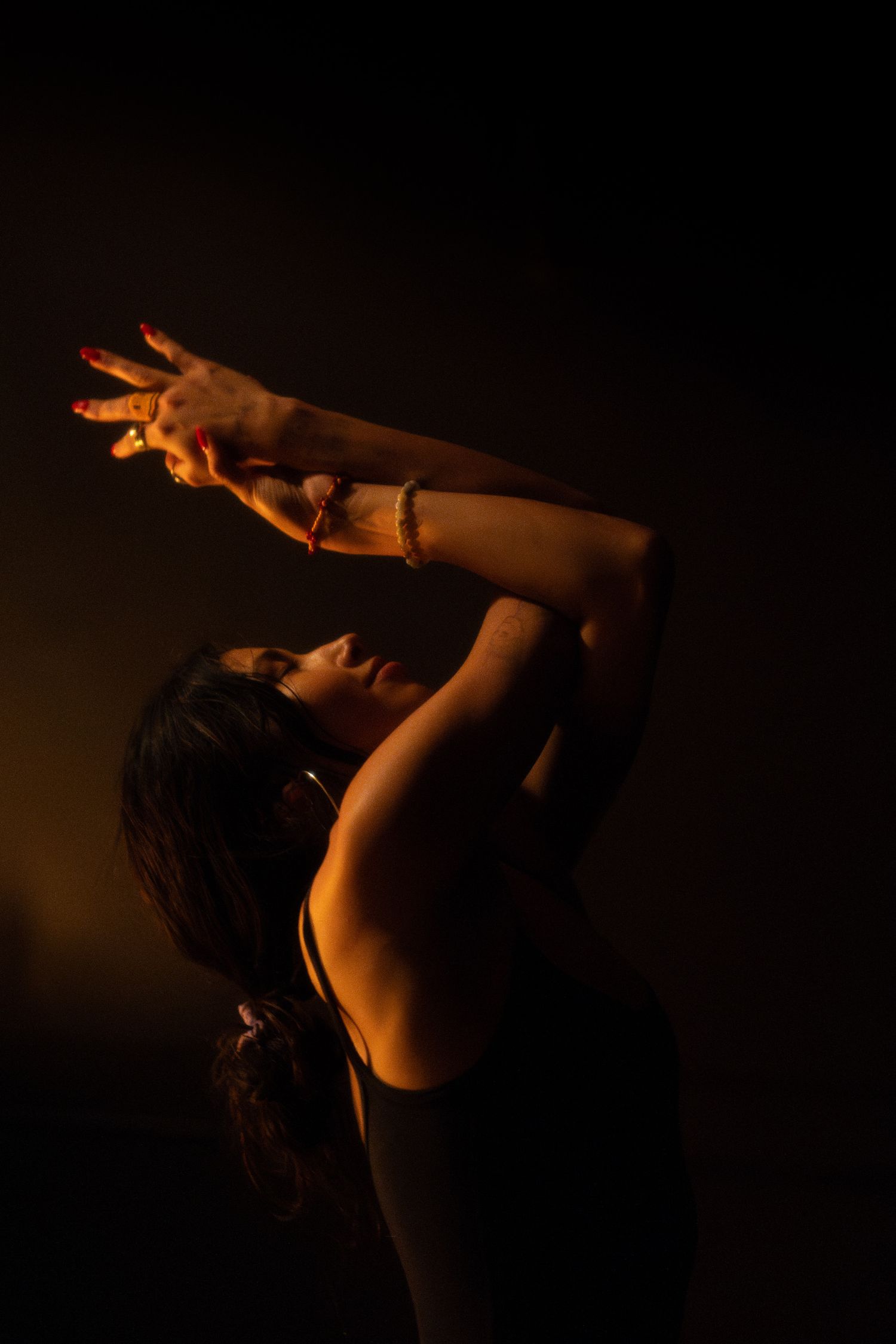 Dramatic silhouette of a dancer with raised arms against a dark background.