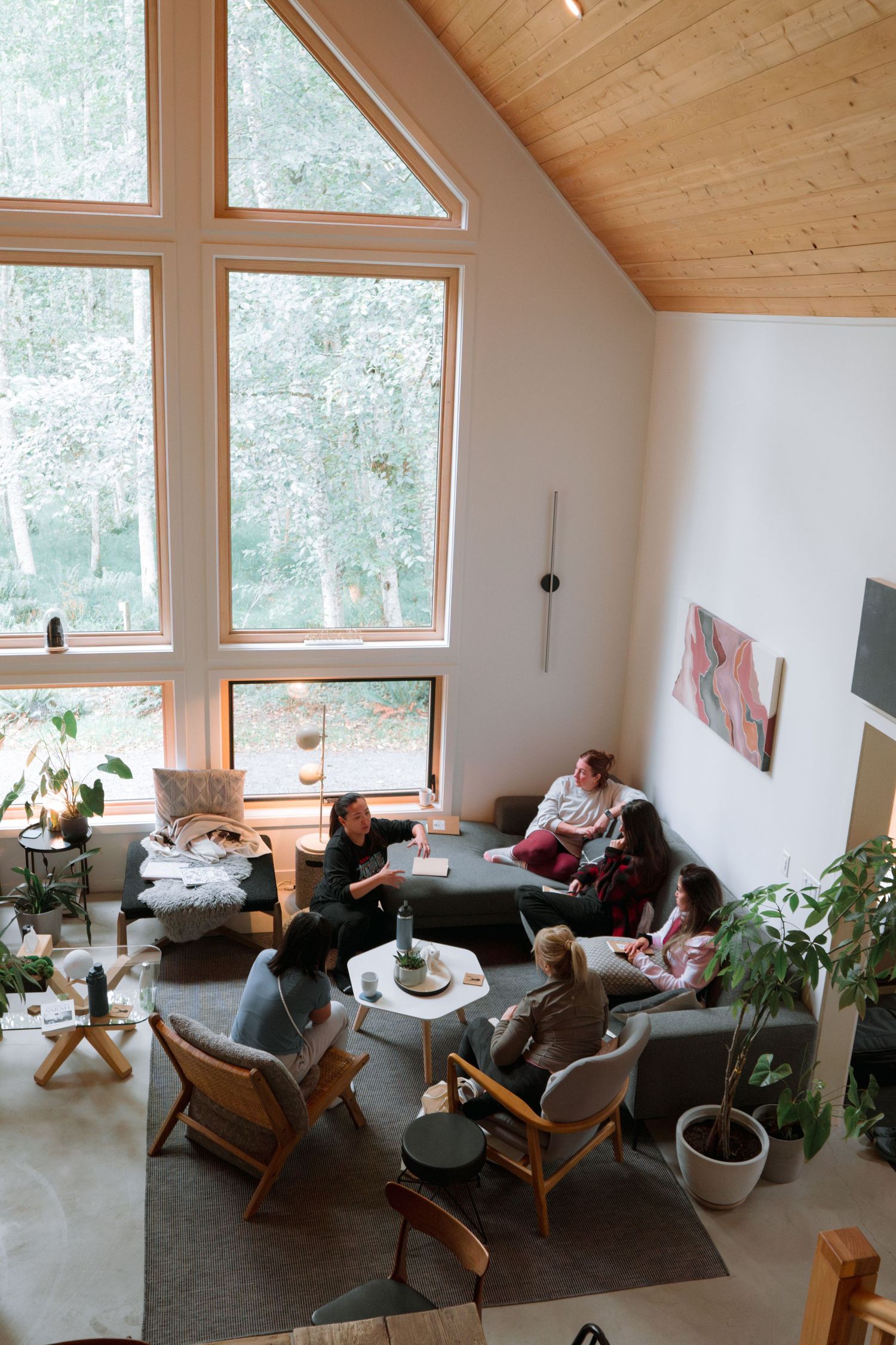 Modern living space with vaulted ceiling, large windows, and comfortable seating arrangement.