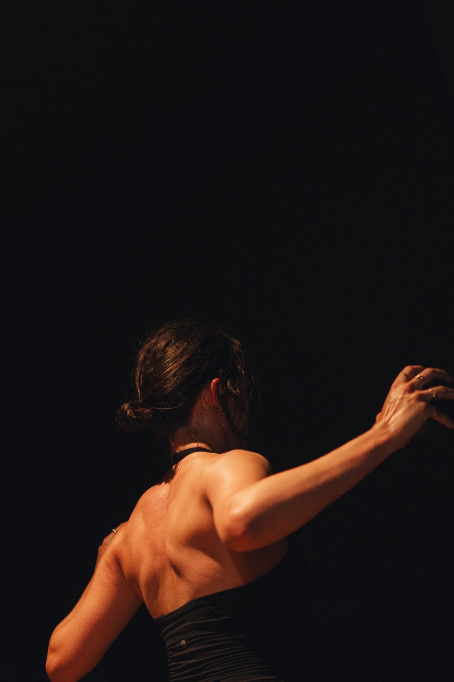 Dramatic lighting illuminates a dancer's muscular back during performance.