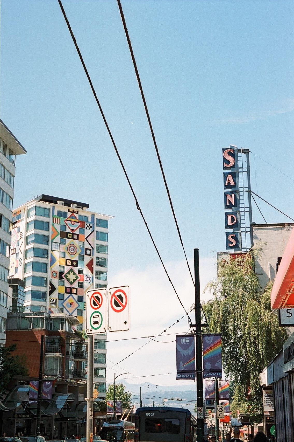 Urban street view with Sands sign and power lines against blue sky in downtown area.