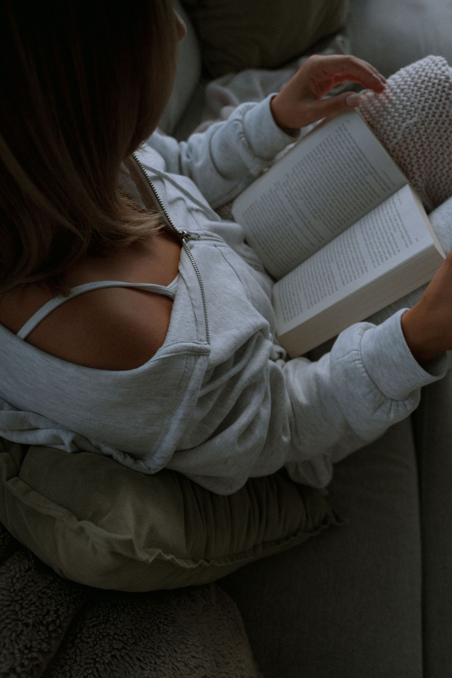 Overhead view of person reading book in comfortable white loungewear.