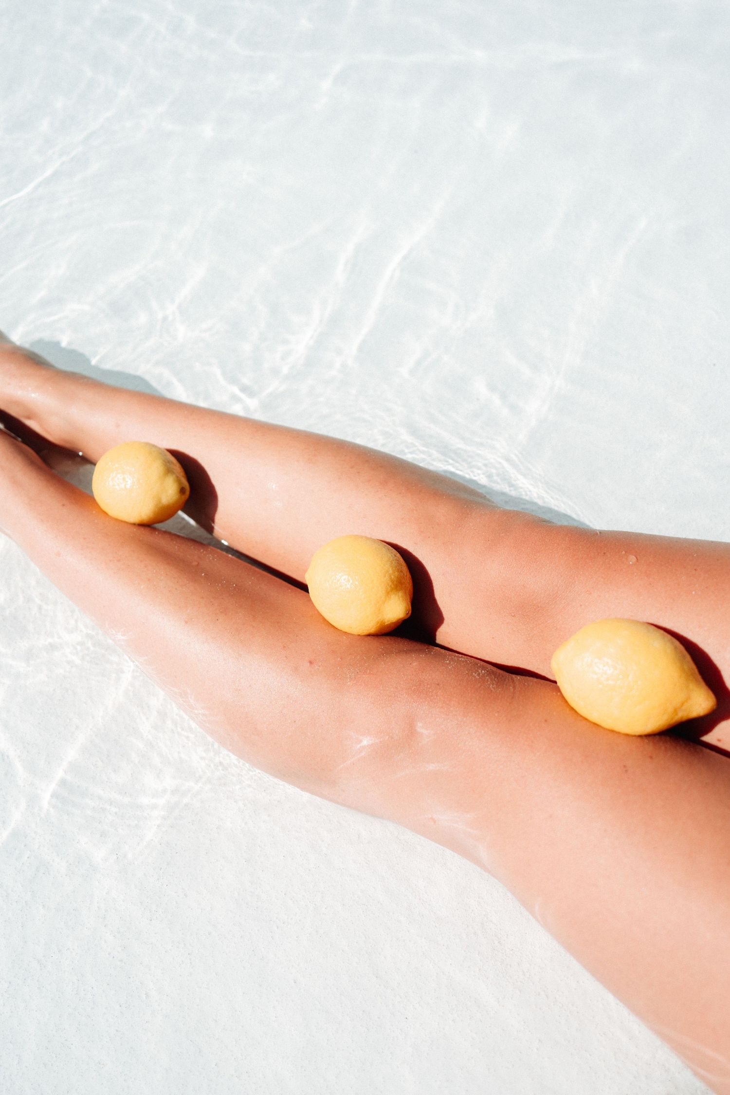 Three oranges lined up on a peach-colored surface against a light background.