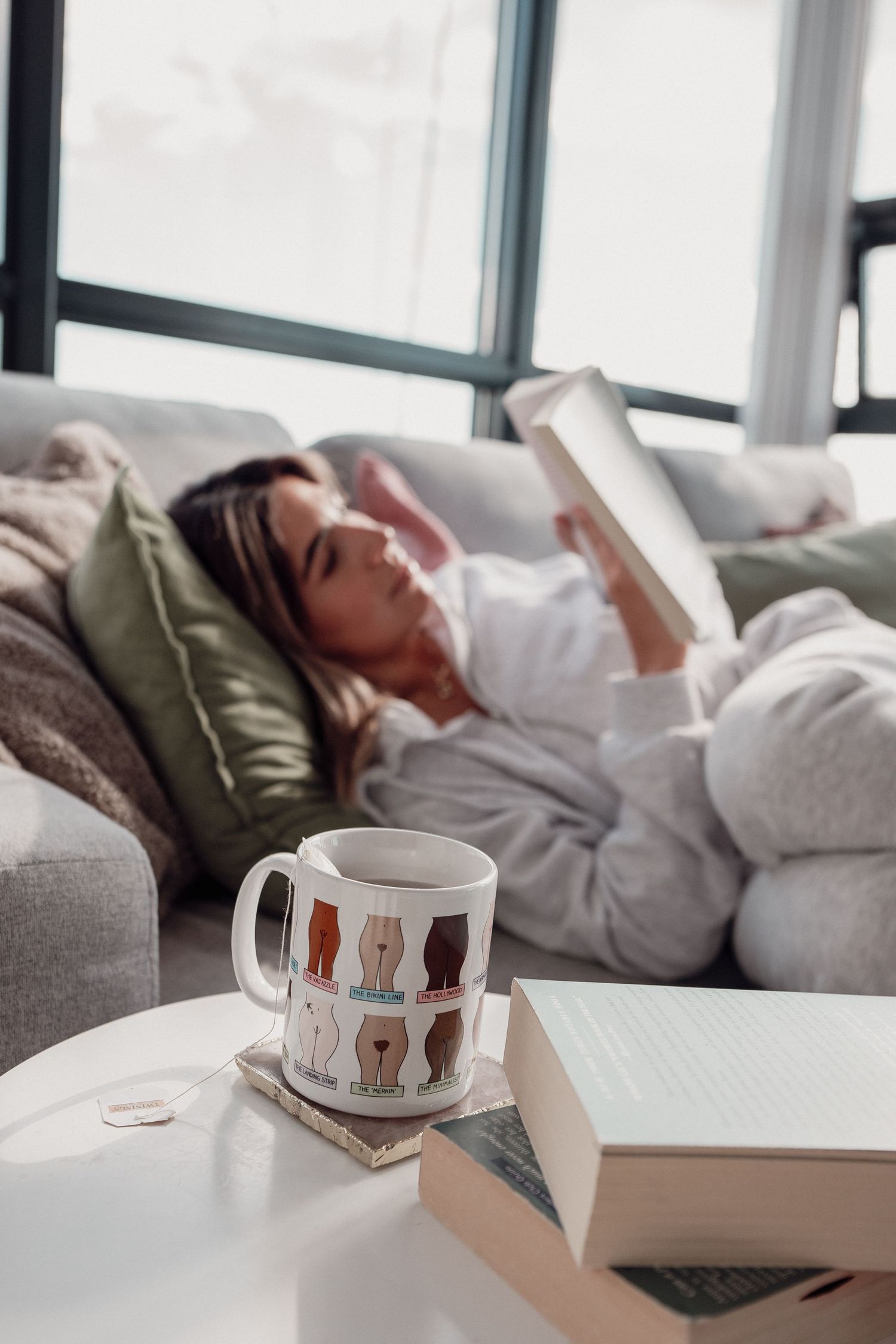 Cozy reading nook with decorative cat mug and book on side table.