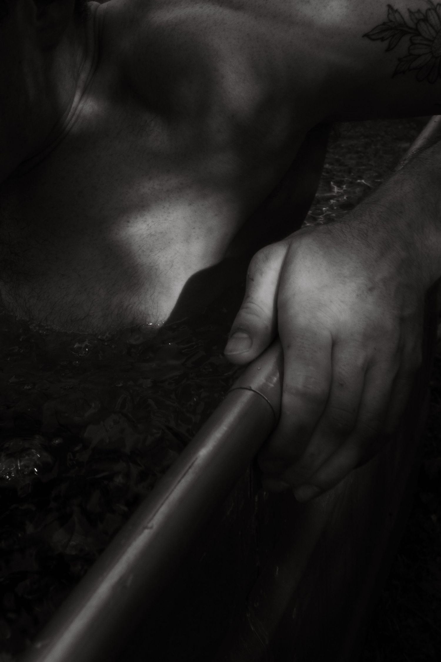 Artsy black and white photograph of hand gripping a metal rail in moody lighting.