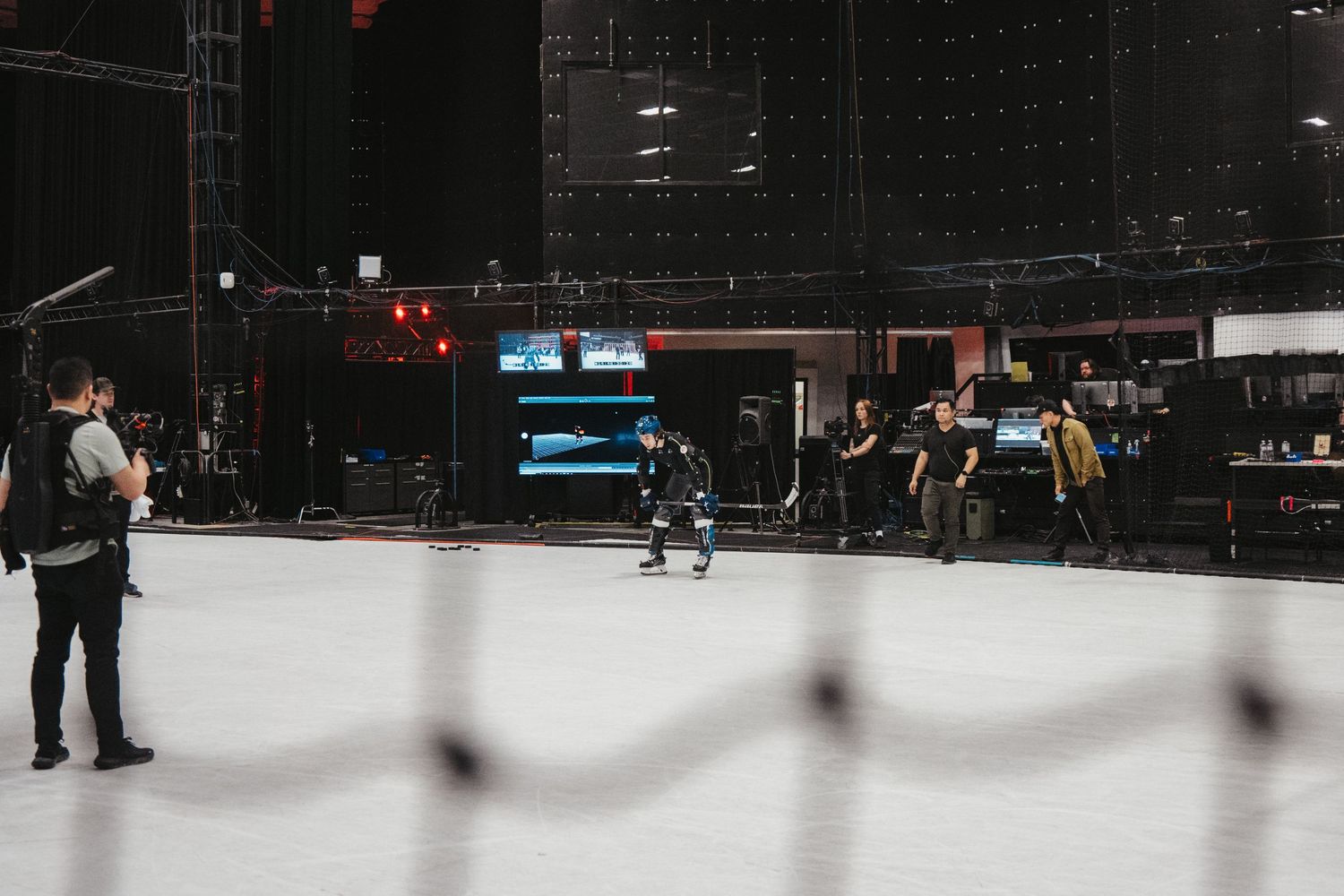 Wide shot of people on an indoor ice rink with production equipment visible.