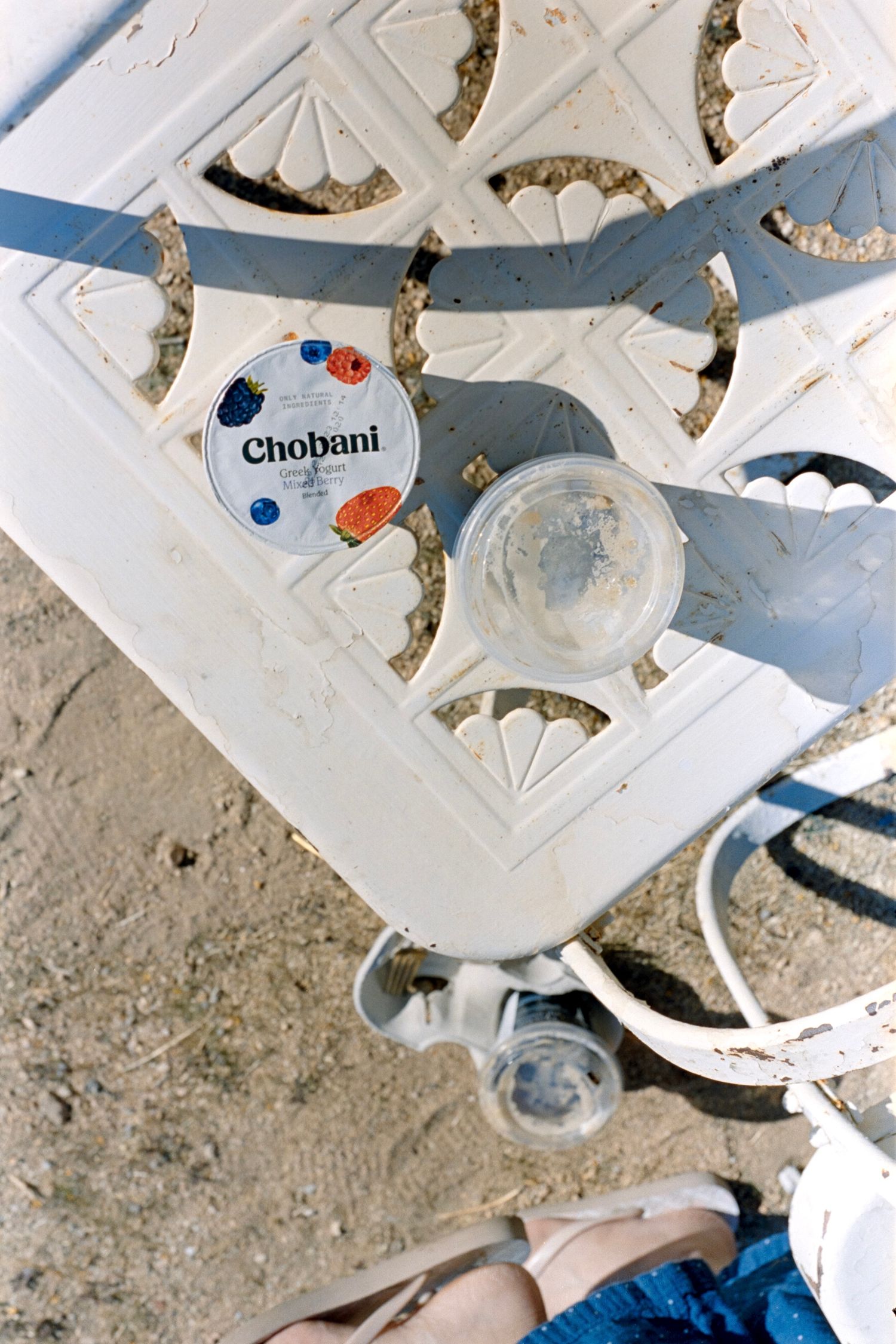 Chobani yogurt container and other items on decorative white surface with geometric patterns.