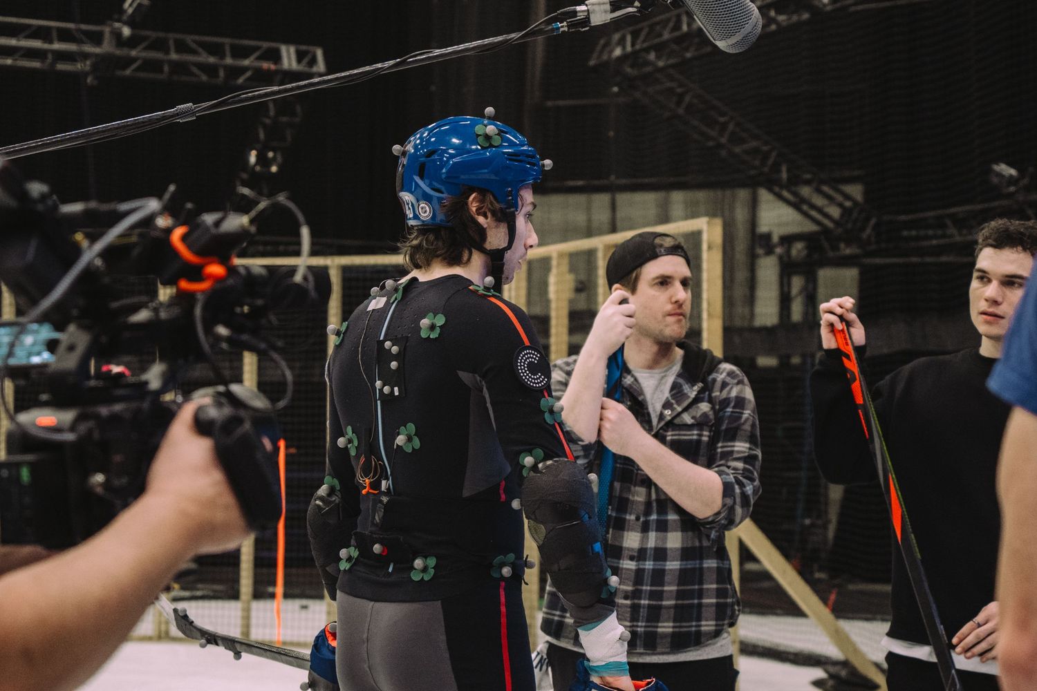 Behind-the-scenes photo of motion capture performers and crew on a studio set.