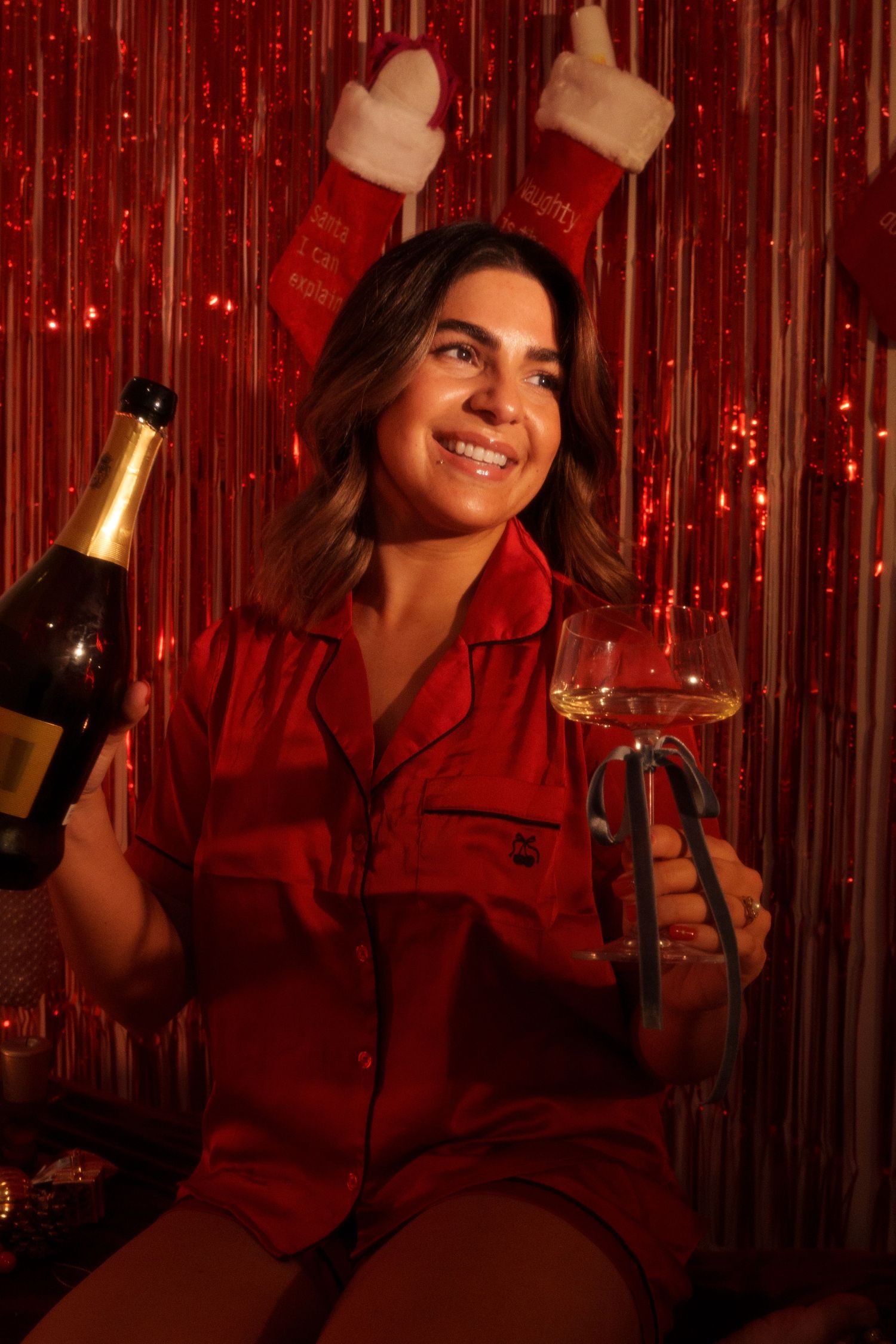 Holiday celebration with red decorations and champagne against sparkly backdrop.