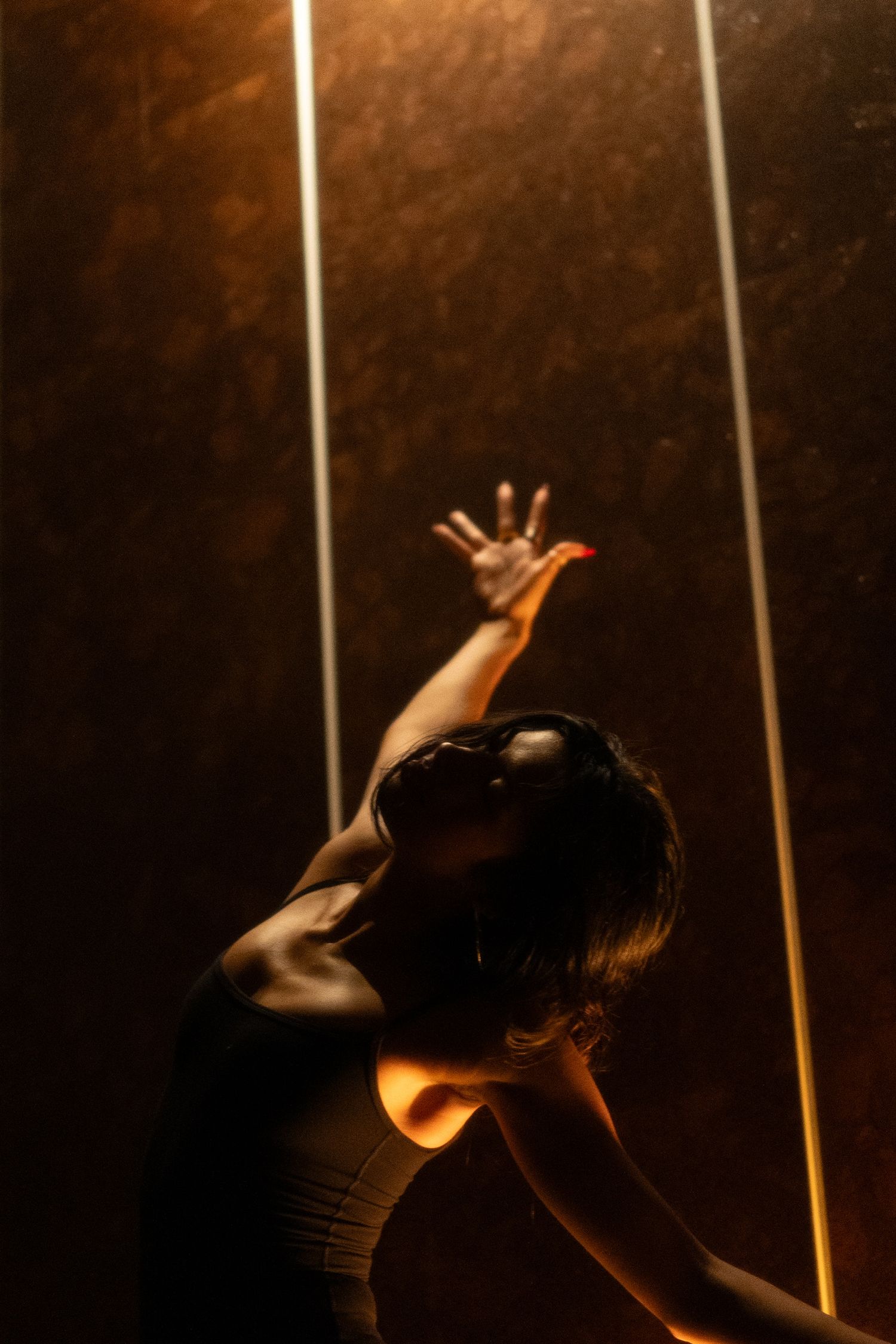 Modern dance performance captured in dramatic lighting with vertical light beams.