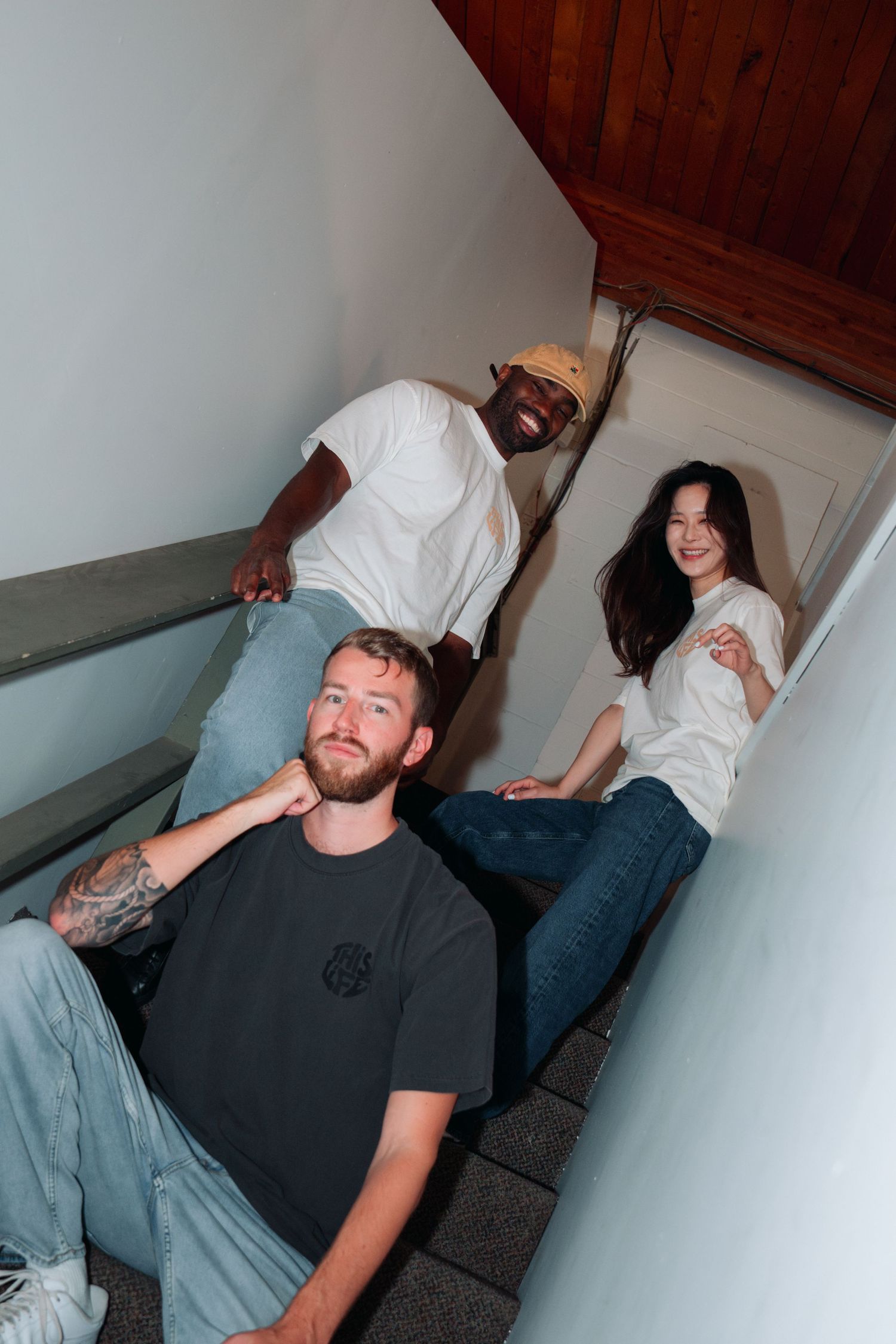 Group of people sitting casually on stairs in casual t-shirts.