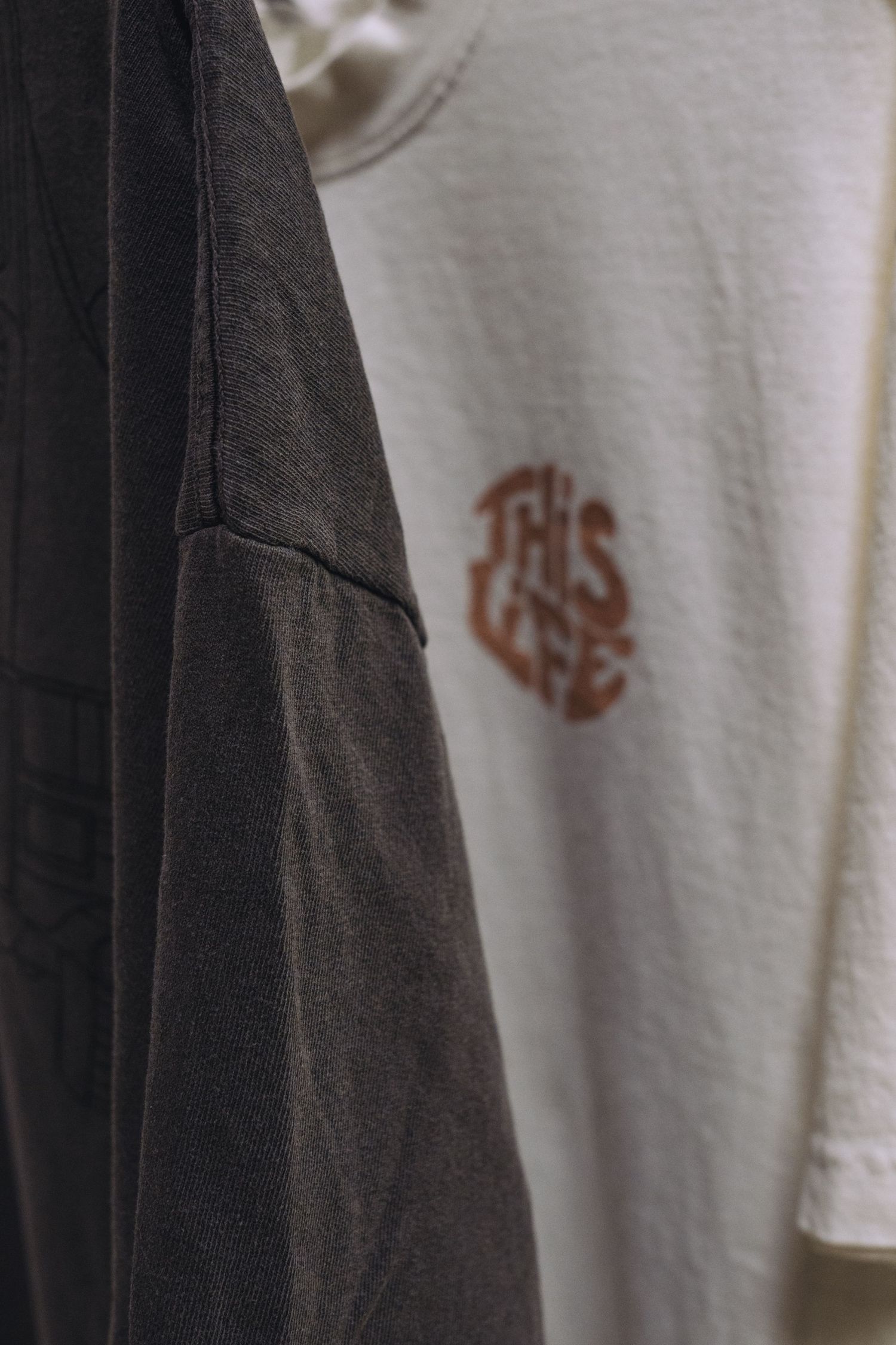 Close-up detail of logo designs on white and black t-shirts.