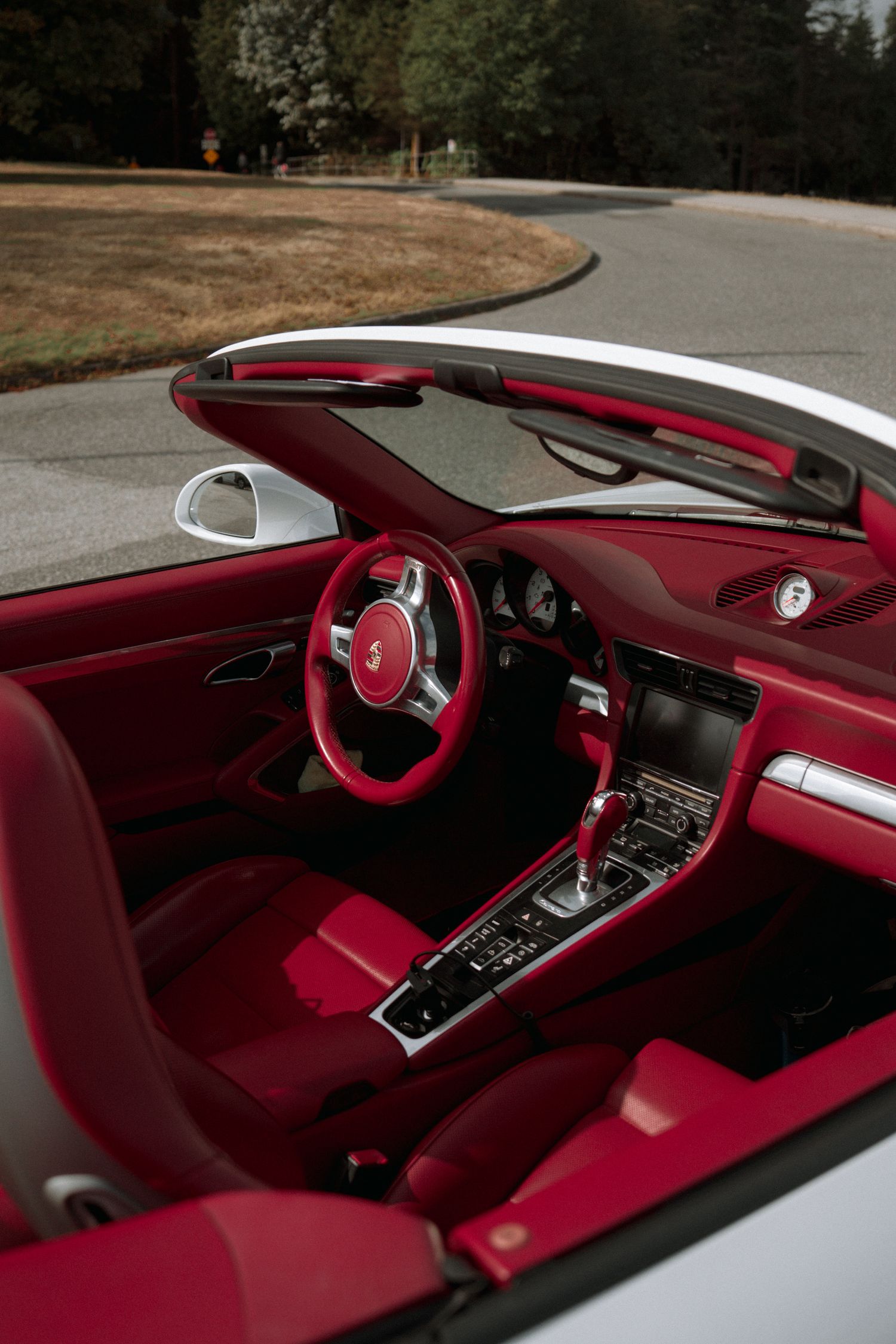 Interior view of a luxury convertible with red leather seats and modern dashboard controls.