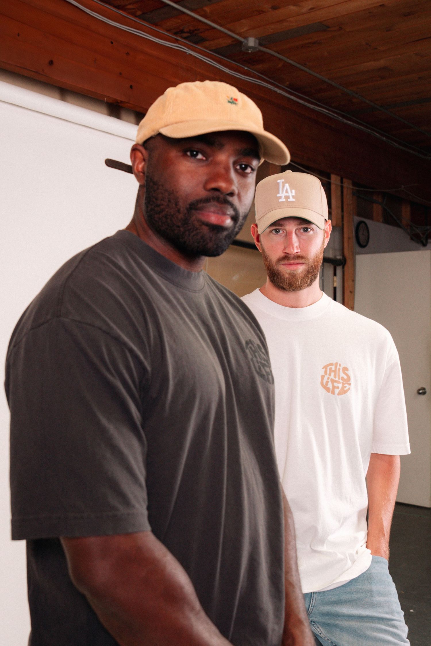 Two people in contrasting white and dark t-shirts pose together in indoor setting.