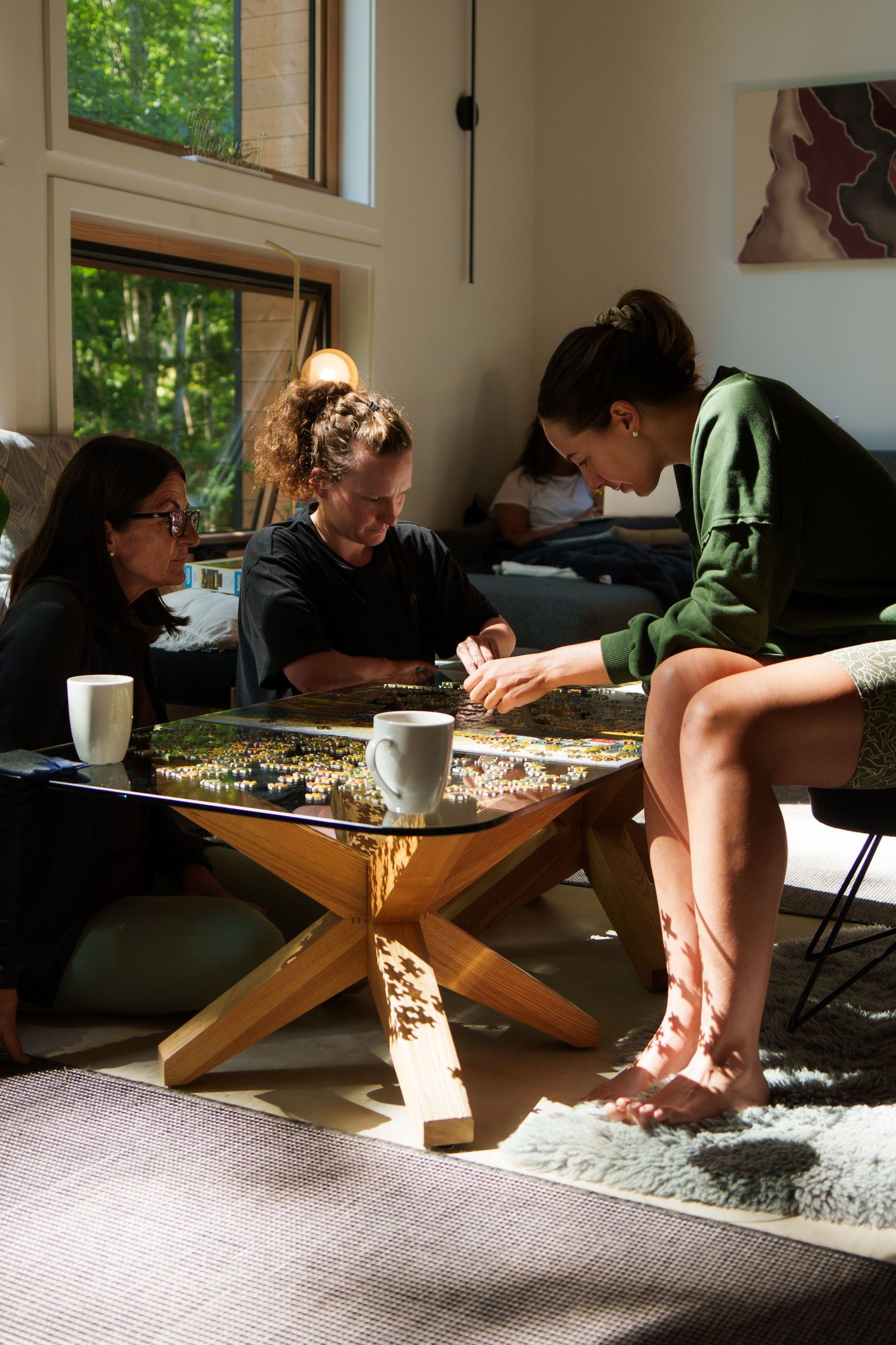 Friends gathered around a wooden coffee table playing a board game in a sunlit room.