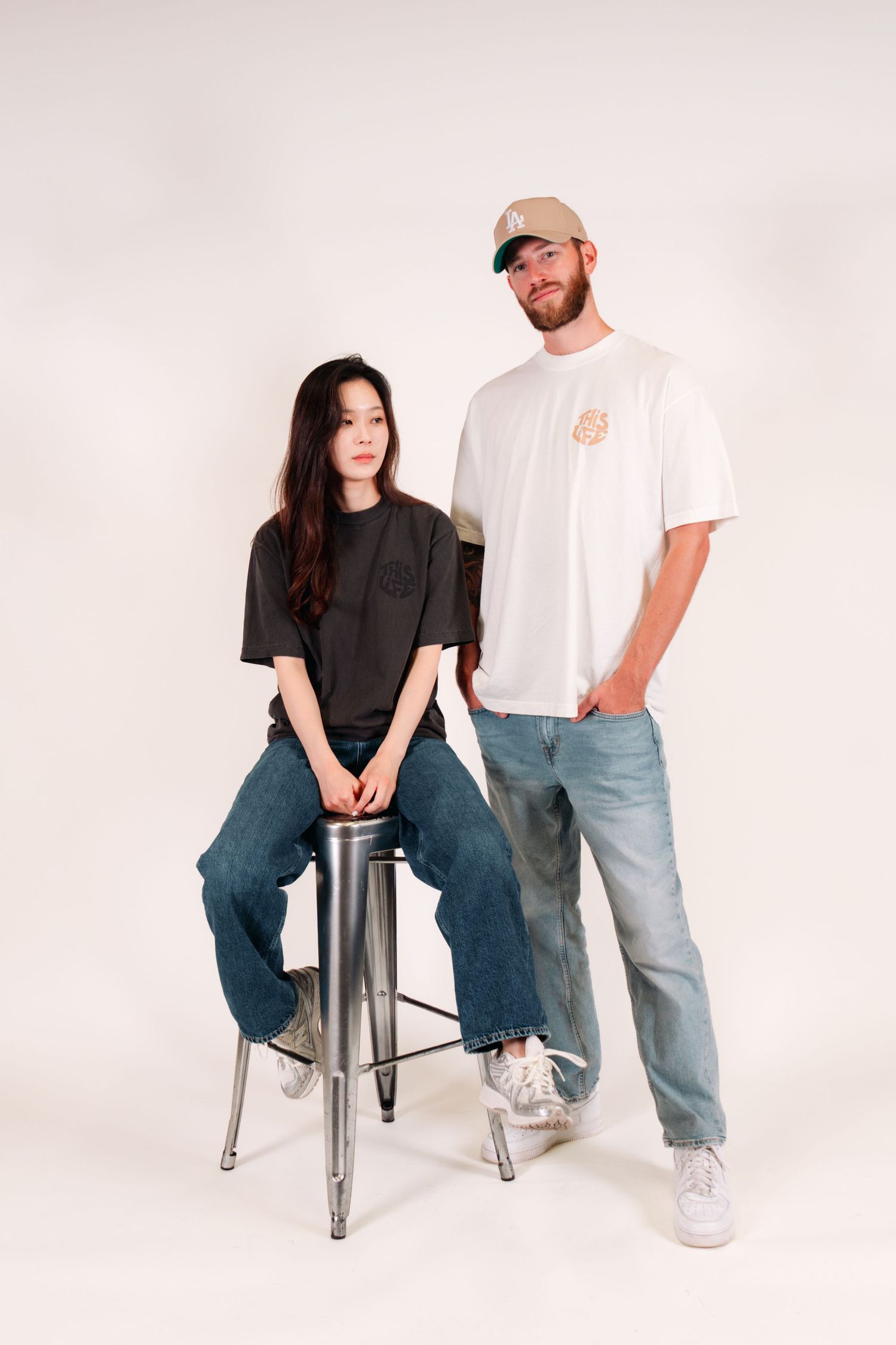 Two people in contrasting black and white t-shirts posing with metal stool.