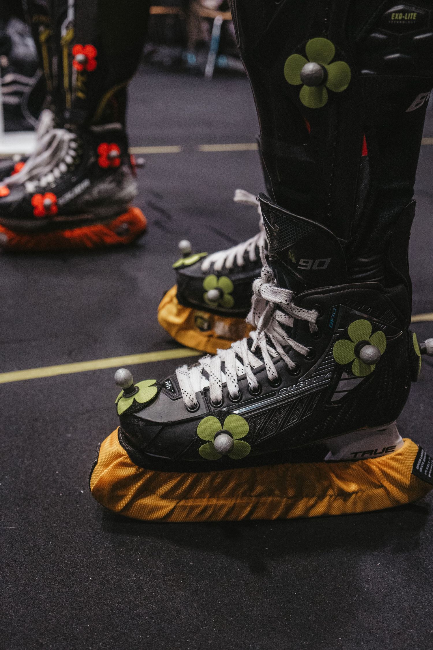 Close-up of black ice skates decorated with green flower details on yellow padding.