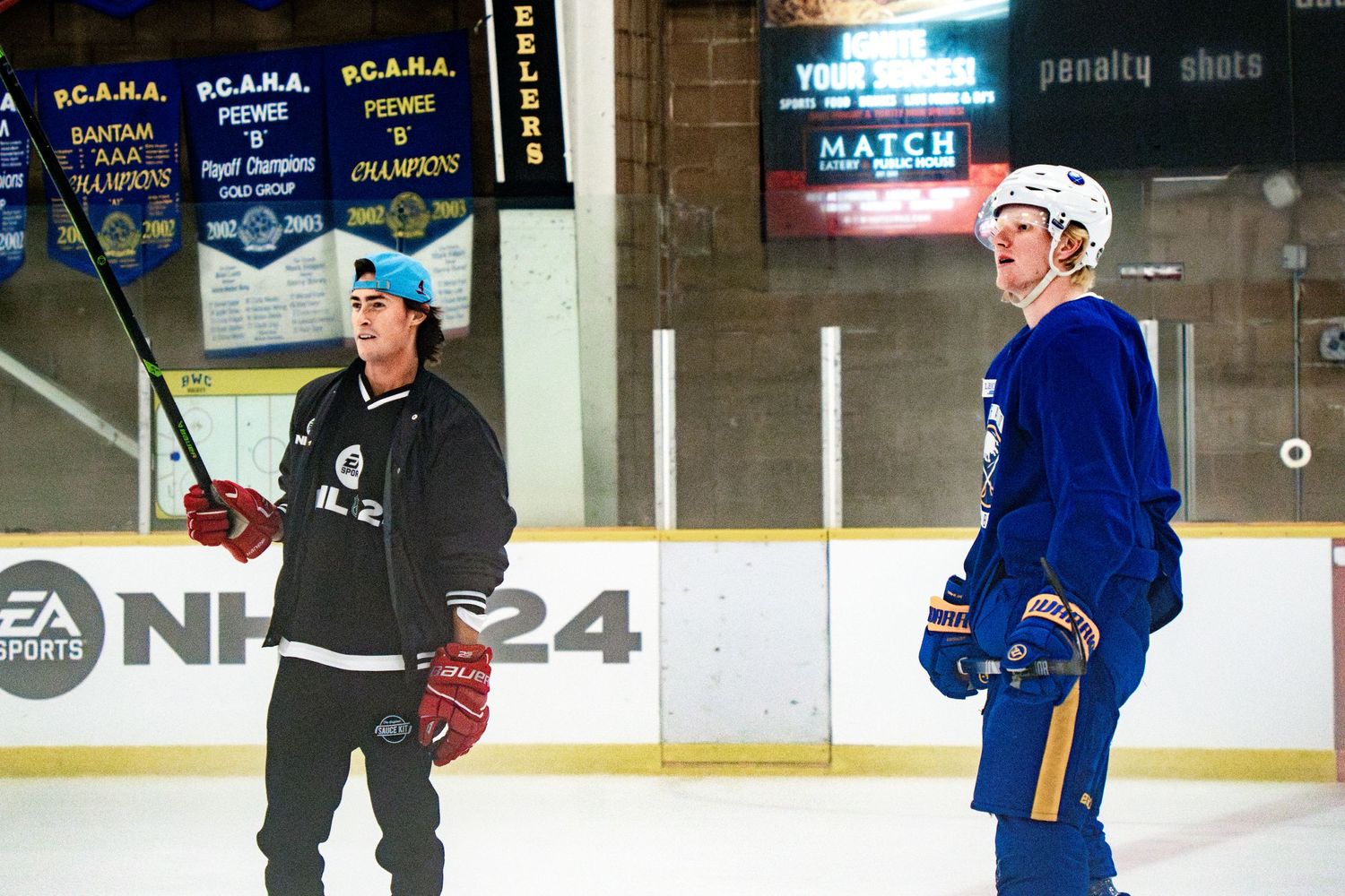 Hockey players practicing on ice with championship banners hanging overhead.