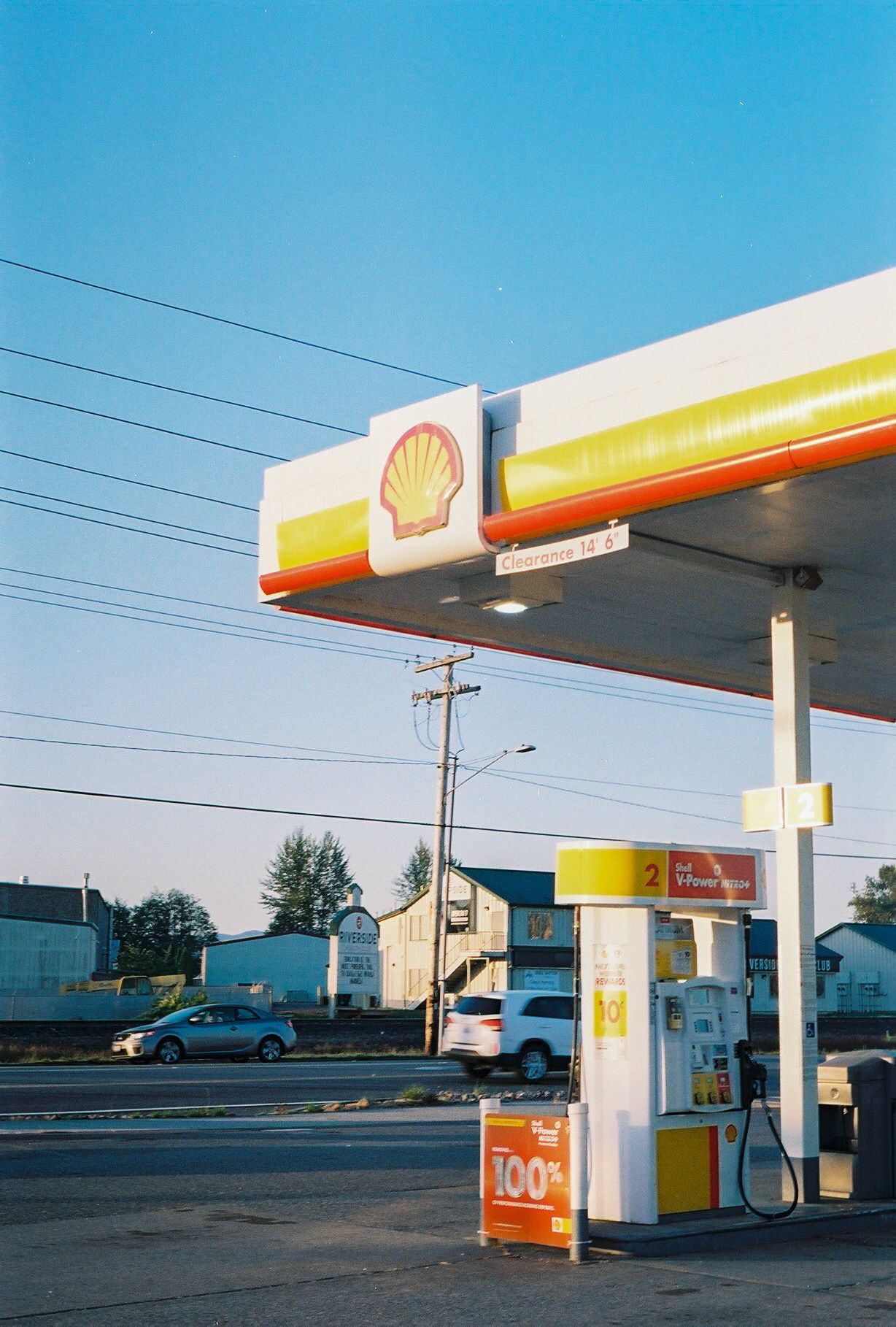 Shell gas station with yellow and red signage against blue sky at dusk.