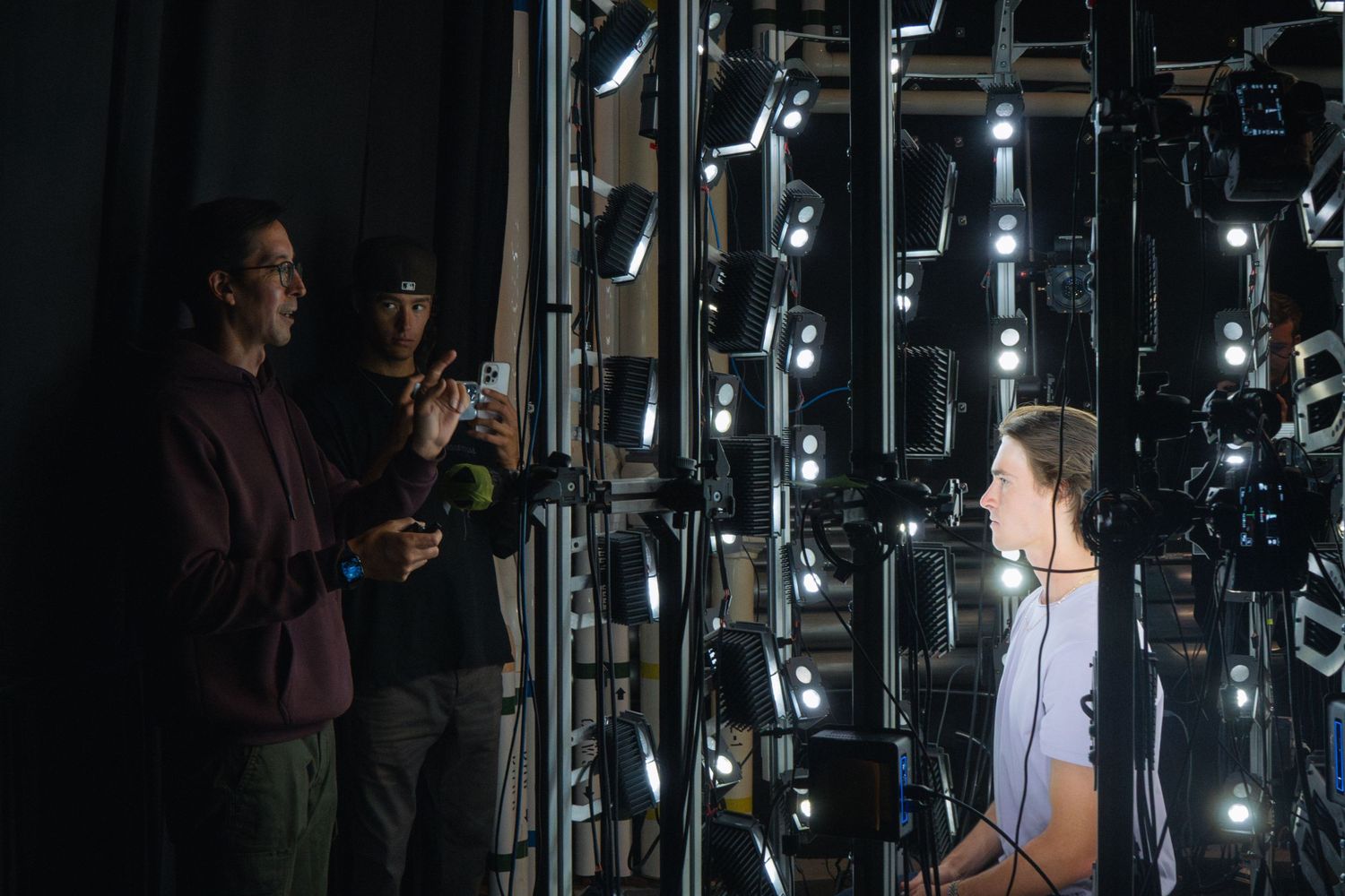 Film crew members discussing in front of illuminated technical setup on set.