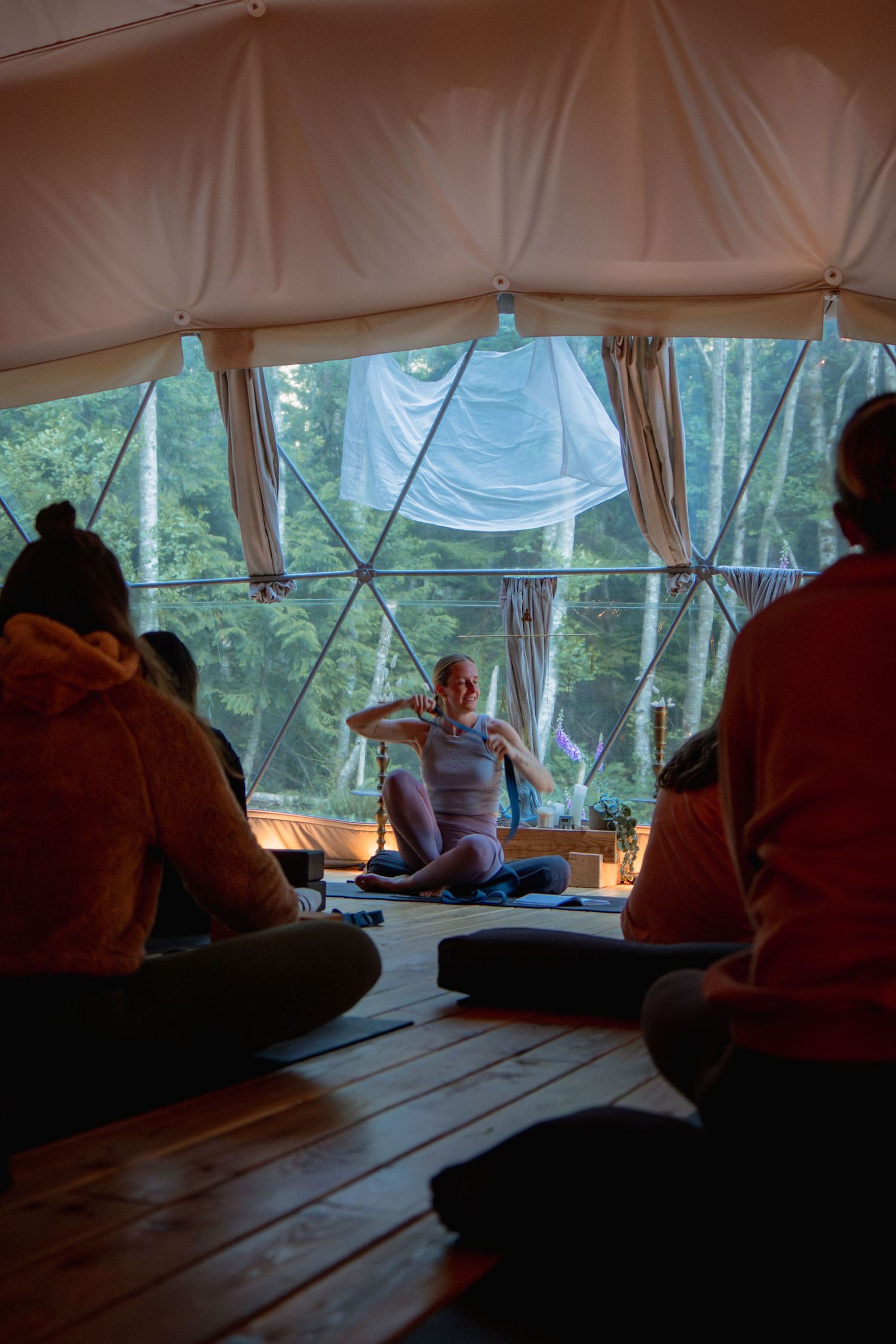 Group meditation or yoga session in a sunlit geodesic dome with forest views.