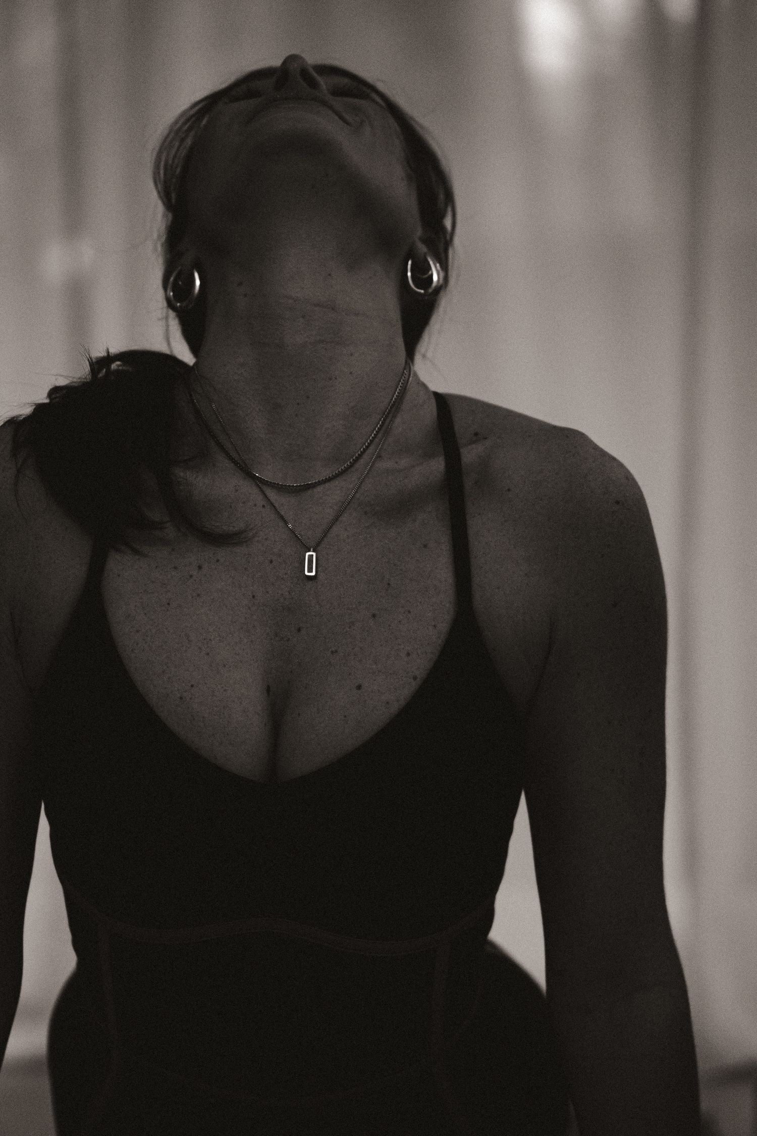 Mysterious monochrome portrait of person in black attire with dramatic lighting.