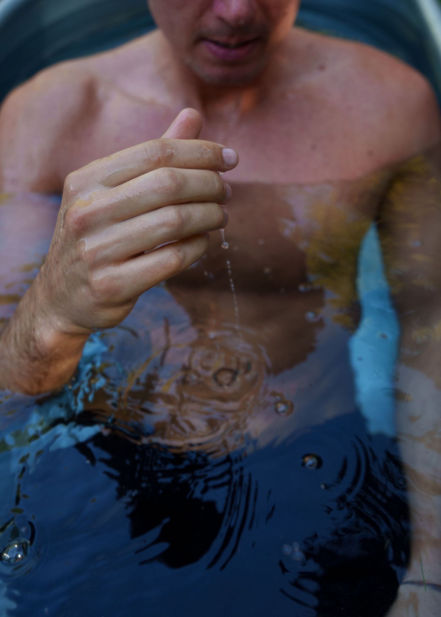 Hands playing with water droplets in a dark atmospheric setting.
