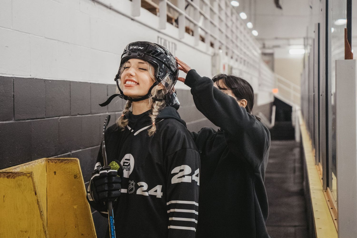 Hockey player in black jersey with number 24 in arena hallway.