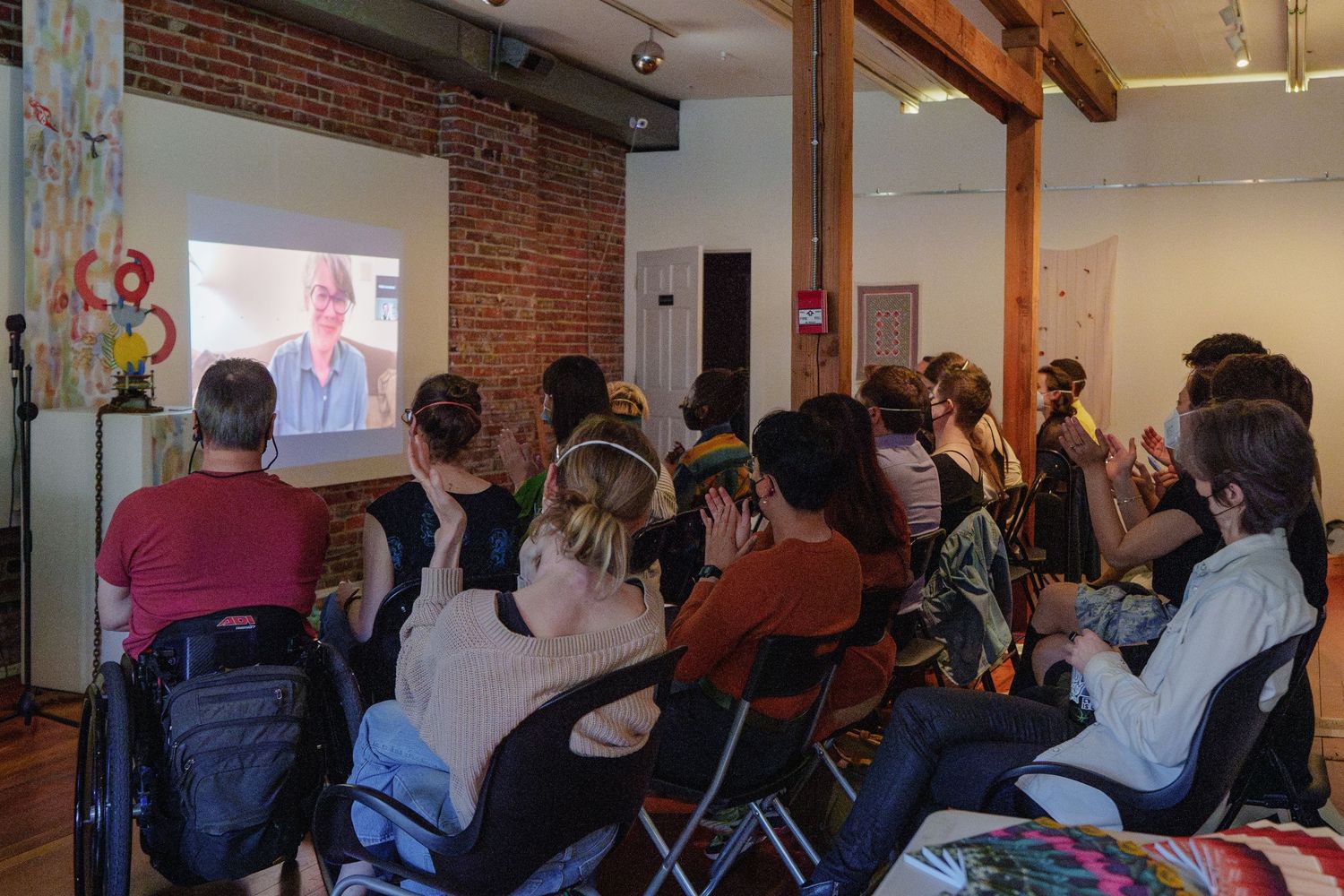 Audience watches presentation in brick-walled room with exposed beams.
