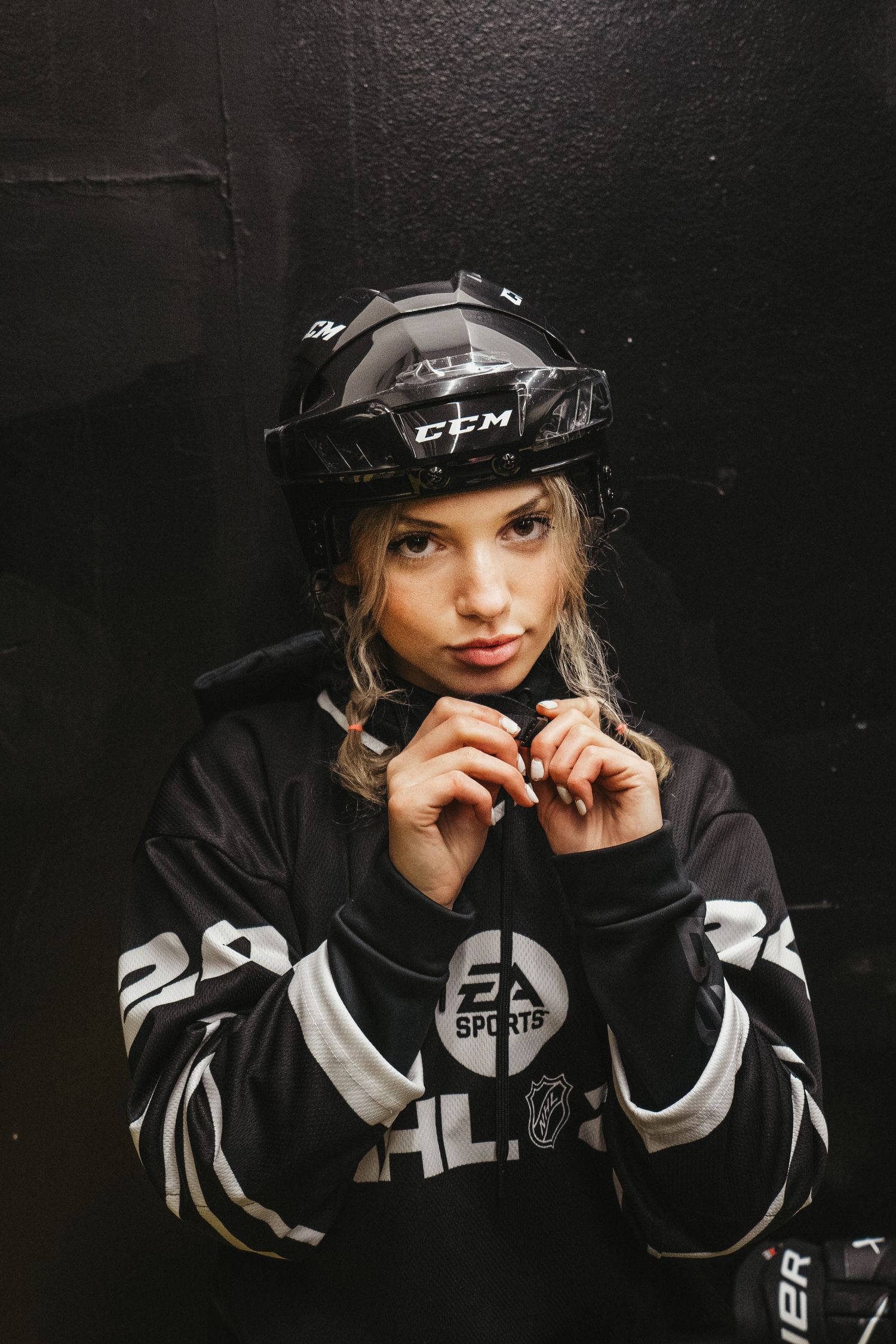 Hockey player in black jersey and CCM helmet against dark background.