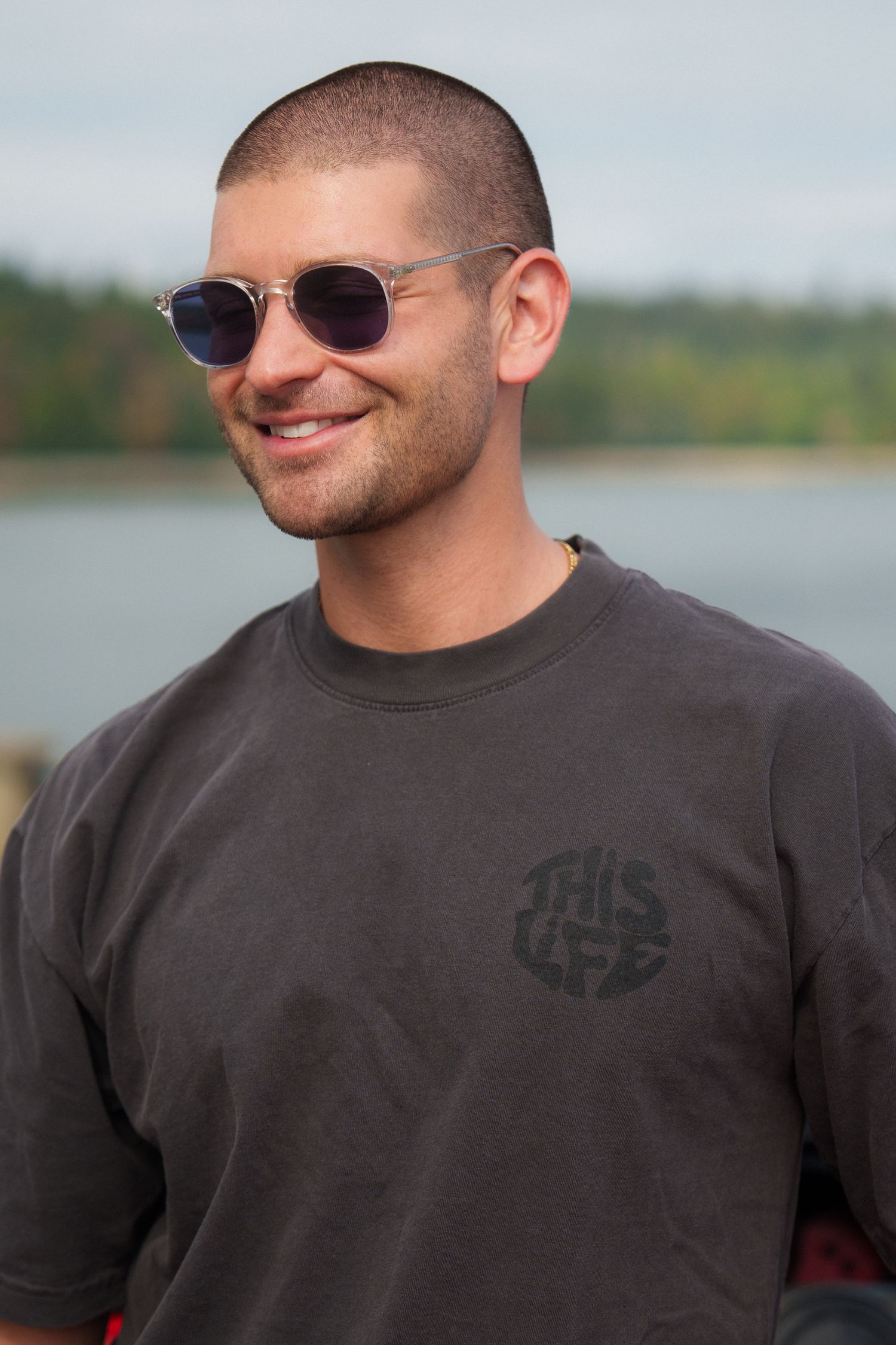 Person wearing sunglasses and a dark t-shirt outdoors.