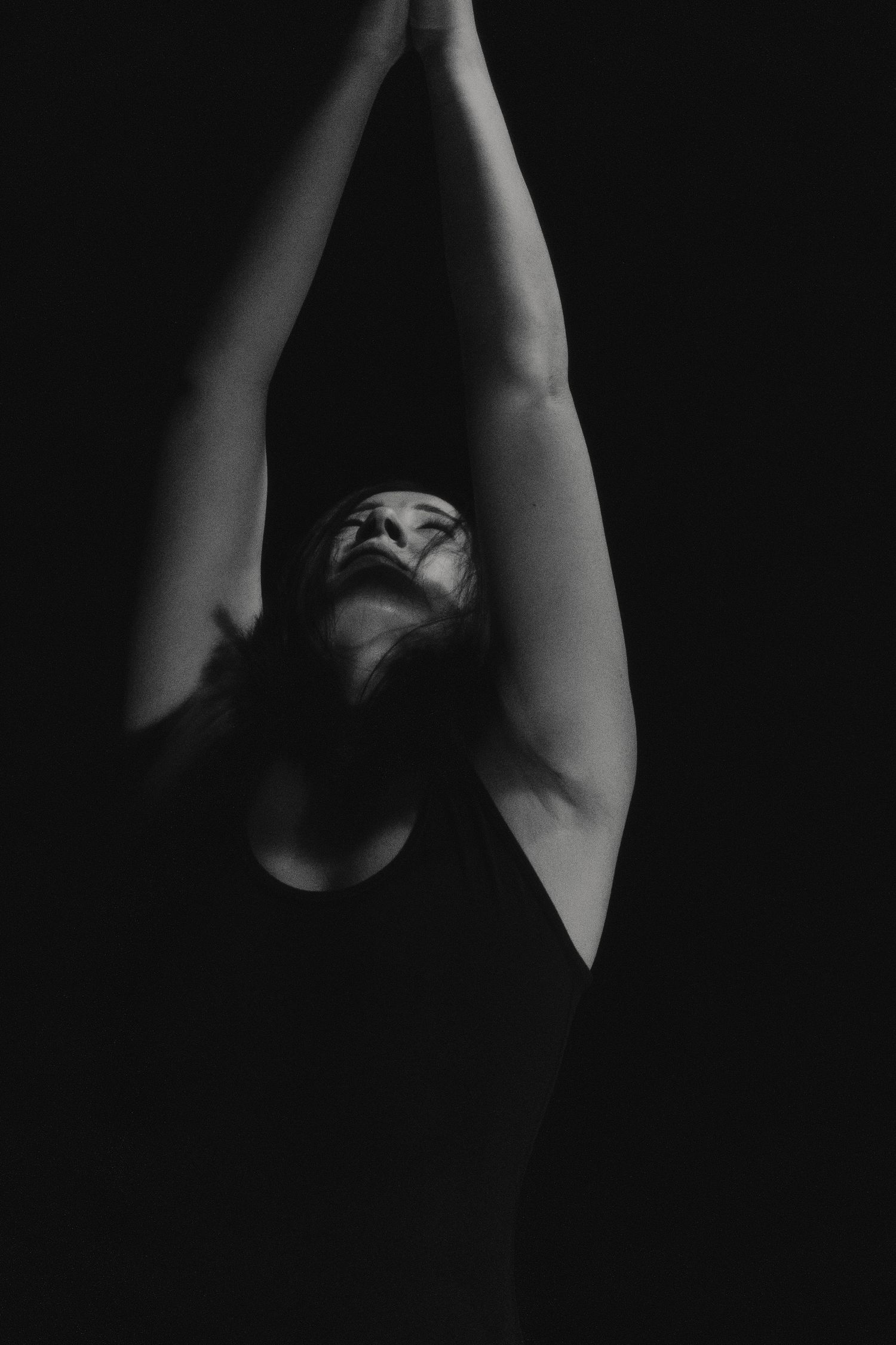 Dramatic black and white portrait of dancer reaching upward in minimalist composition.