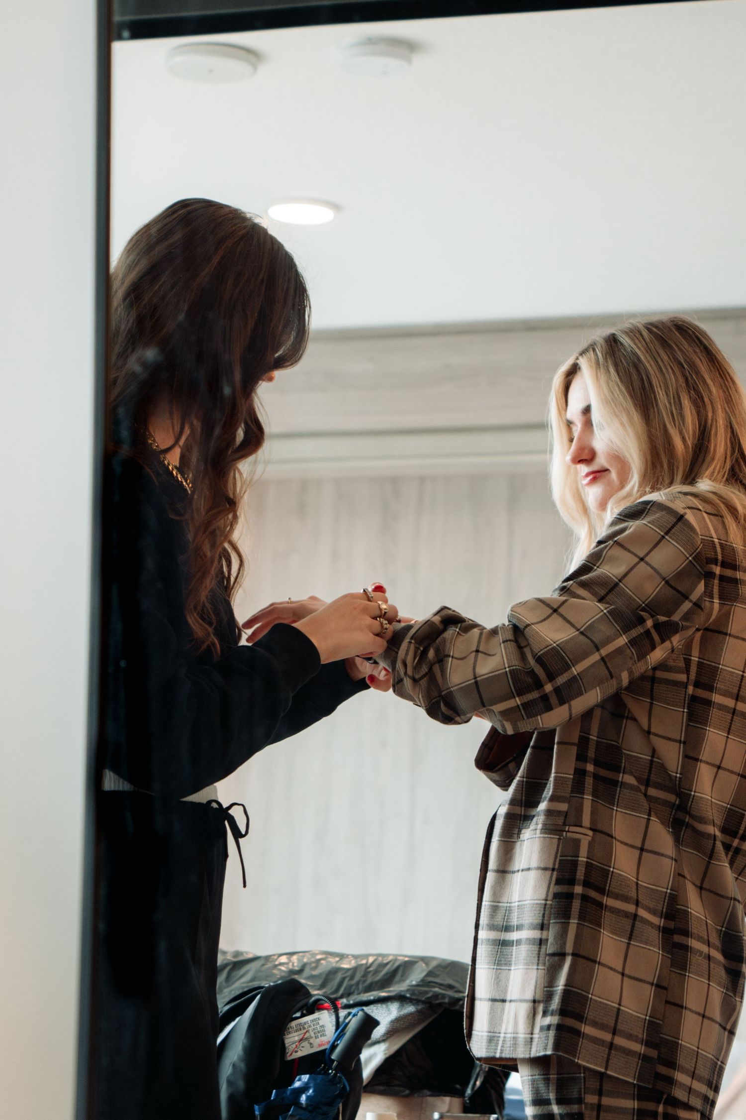 Two people interact while wearing stylish plaid coats in an indoor setting.